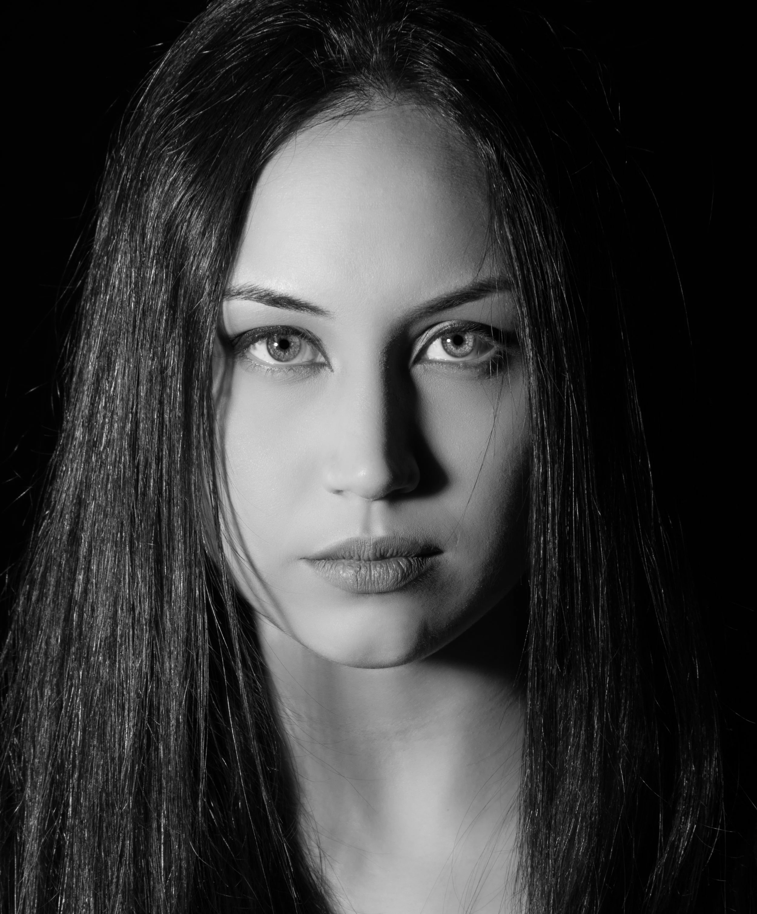Retrato en blanco y negro de una mujer con cabello largo y ojos claros, mirando fijamente a la cámara.