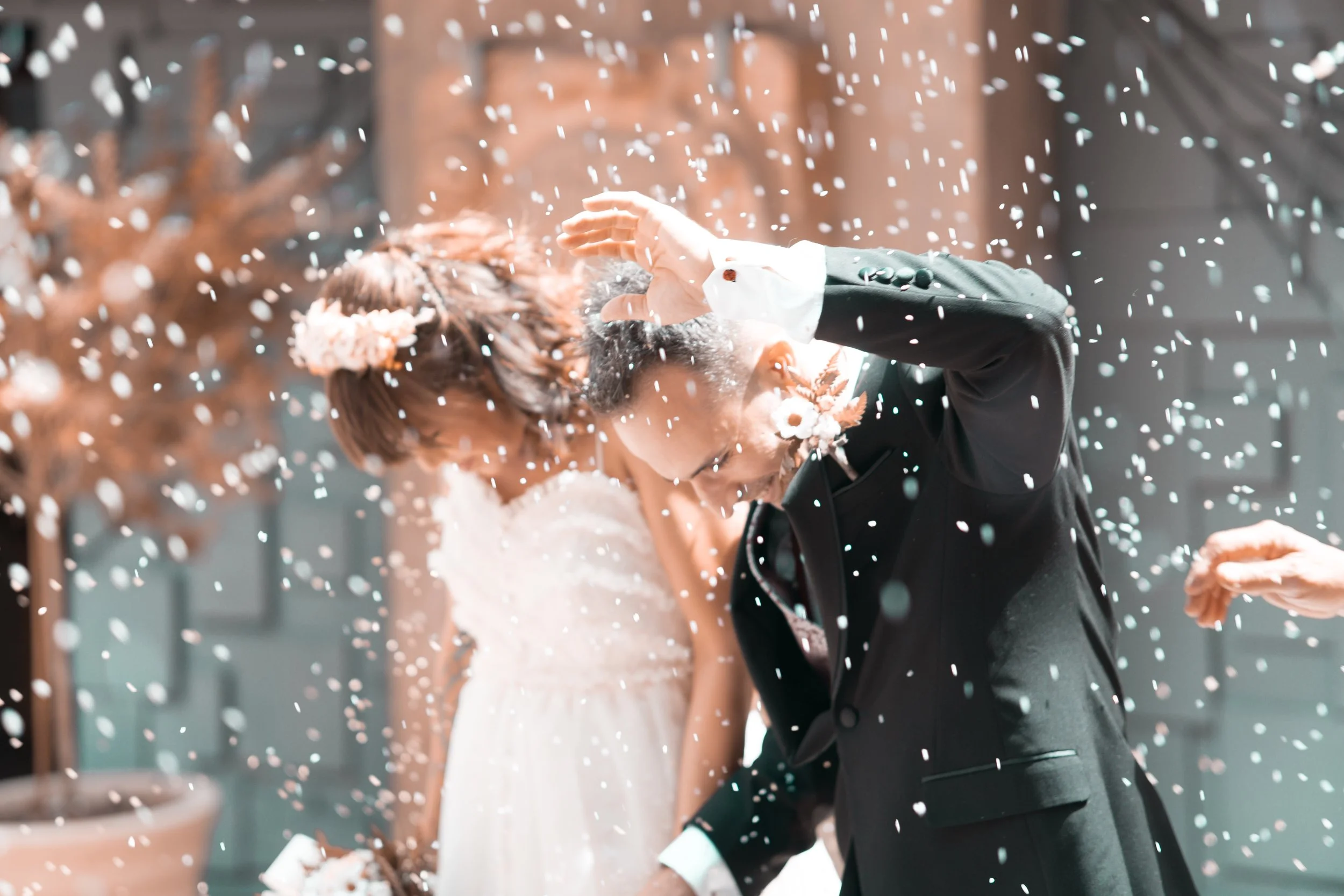 Pareja de recién casados celebrando con confeti en la cabeza en una boda al aire libre.