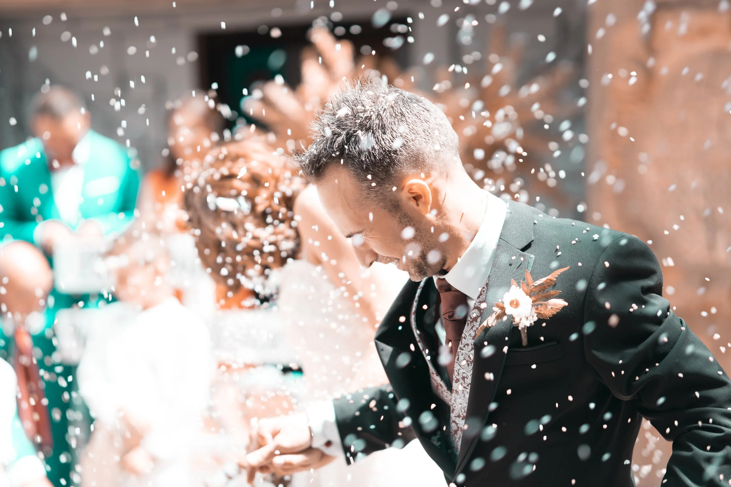 Hombre en traje de boda con confeti en una celebración nupcial.
