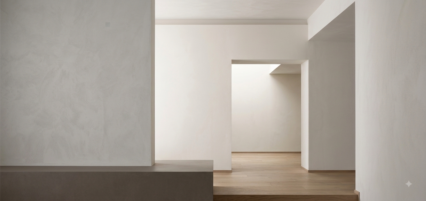 Empty, white-walled interior with wooden flooring and doorways leading to other rooms