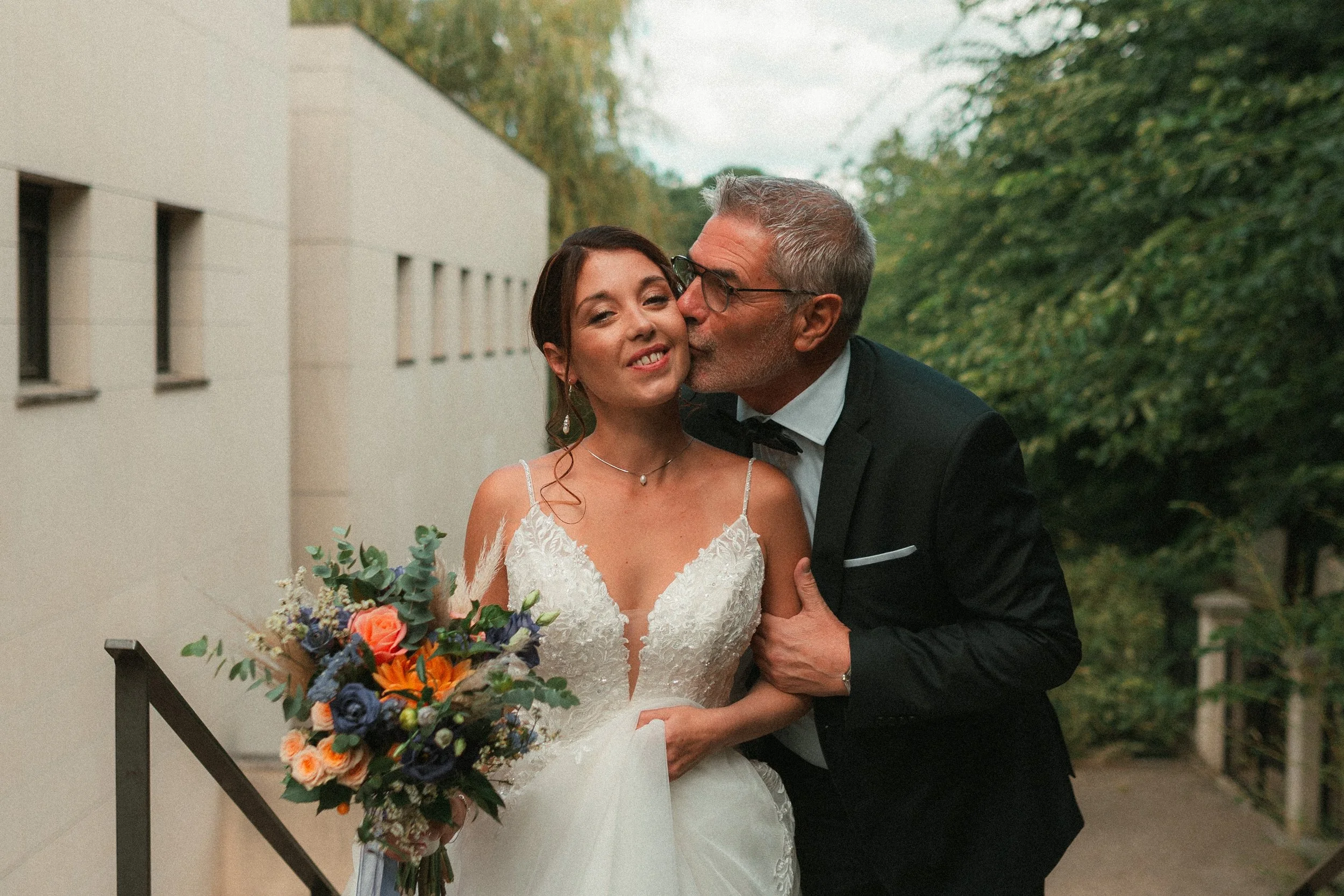 Un couple de mariés, un homme âgé qui embrasse une femme jeune, en robe de mariée, dans un jardin verdoyant