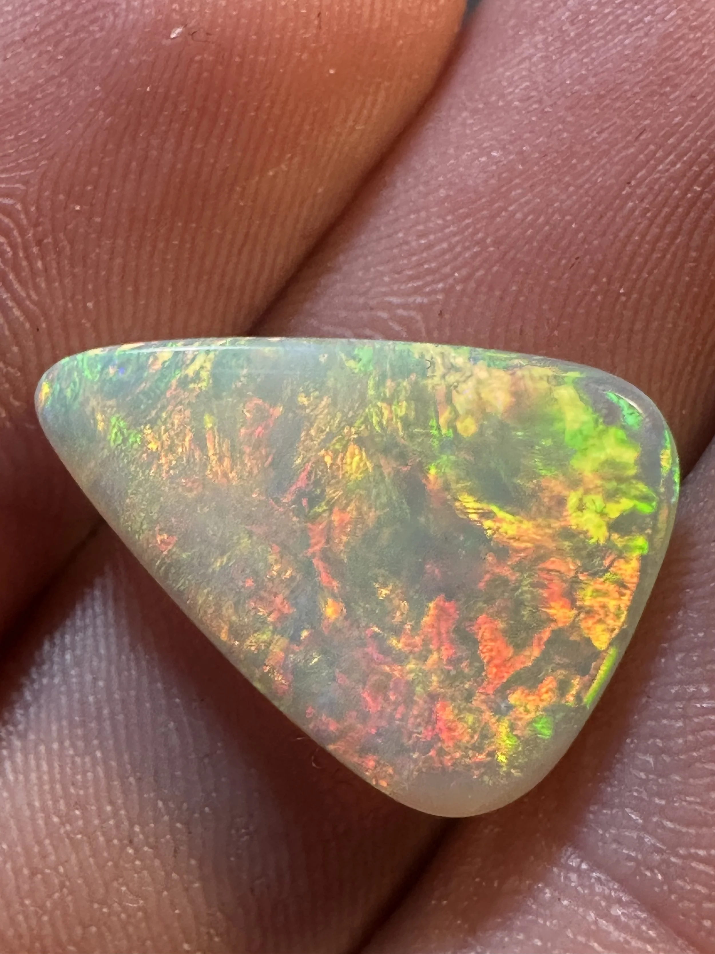 Close-up of an individual’s finger with a holographic nail polish on their fingernail.