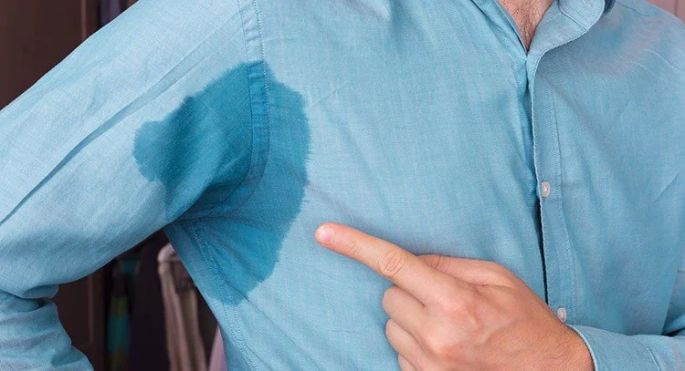 A person wearing a blue shirt with a large, dark stain on the chest area.