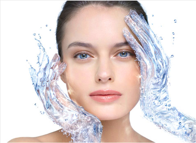Woman with water splashing on her face, holding her cheeks with hands covered in water