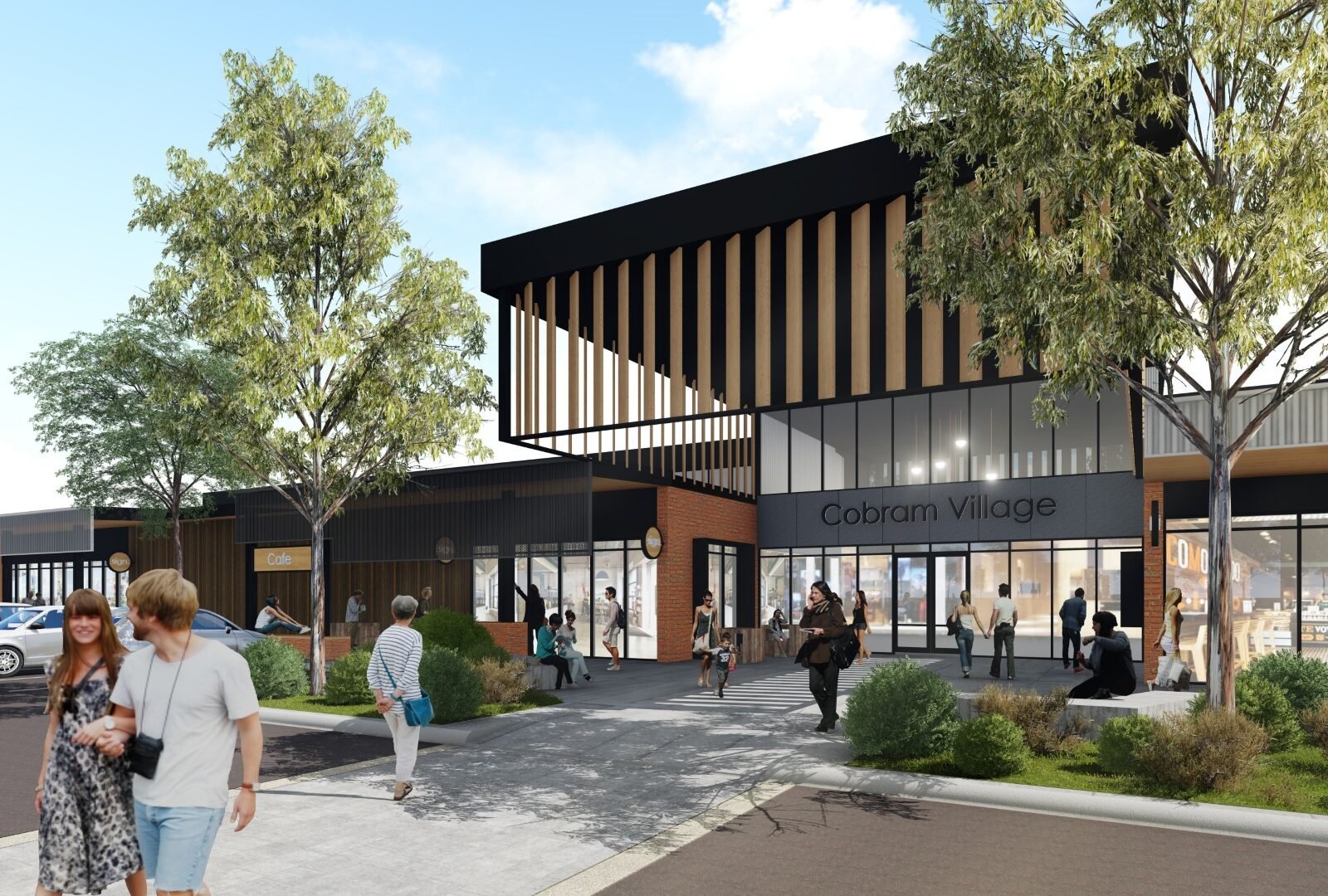 A modern shopping center with a glass storefront, wooden accents, and a sign that reads "Cobram Village." Pedestrians are walking and sitting outside, and there are trees and bushes in the landscaping.