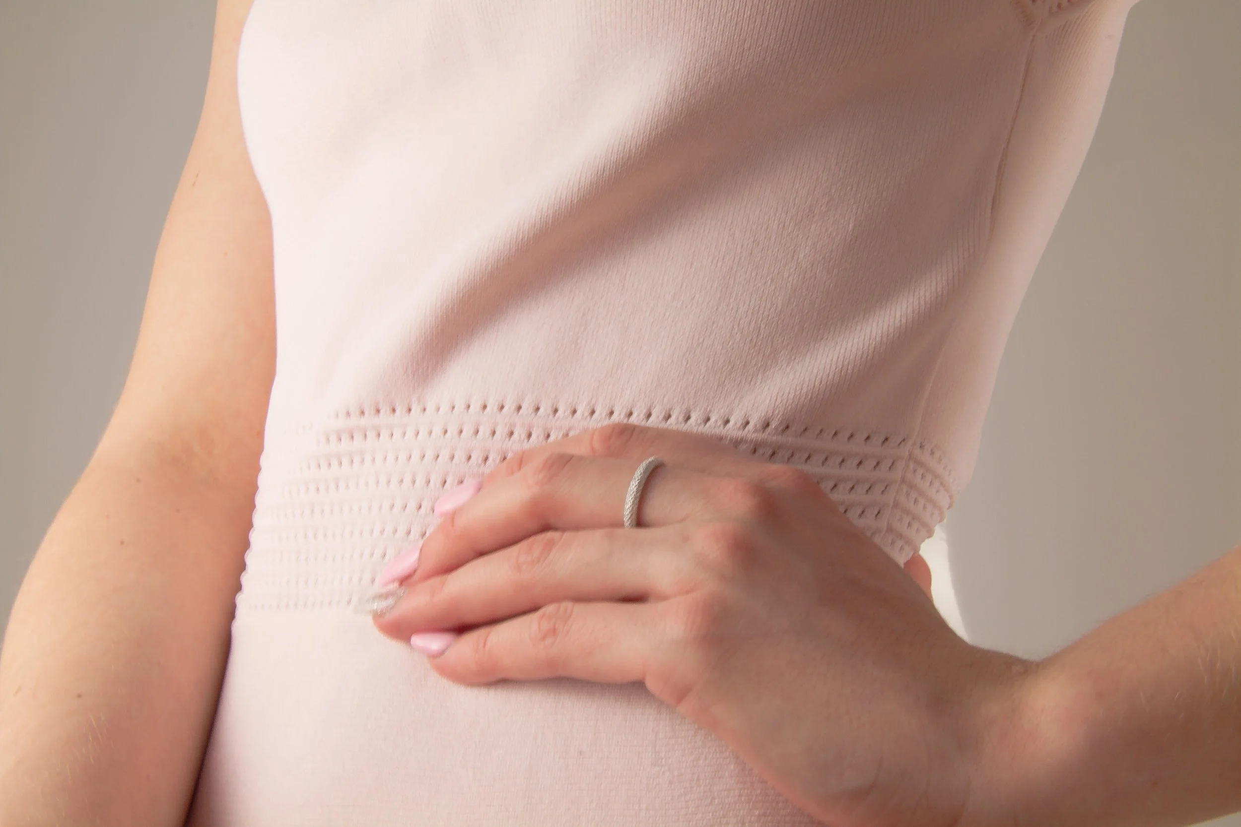 Woman with her hand on her ribcage, practicing breath awareness to release pelvic floor tension