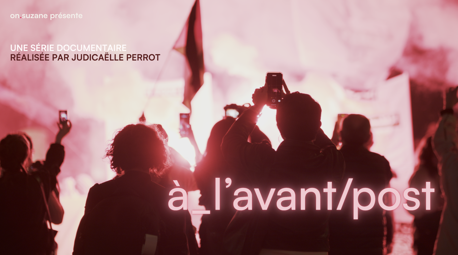Un groupe de personnes dans une foule lors d'une manifestation ou d'un rassemblement, plusieurs tenant leurs téléphones pour prendre des photos ou des vidéos, avec un fond de fumée ou de lumière rouge.