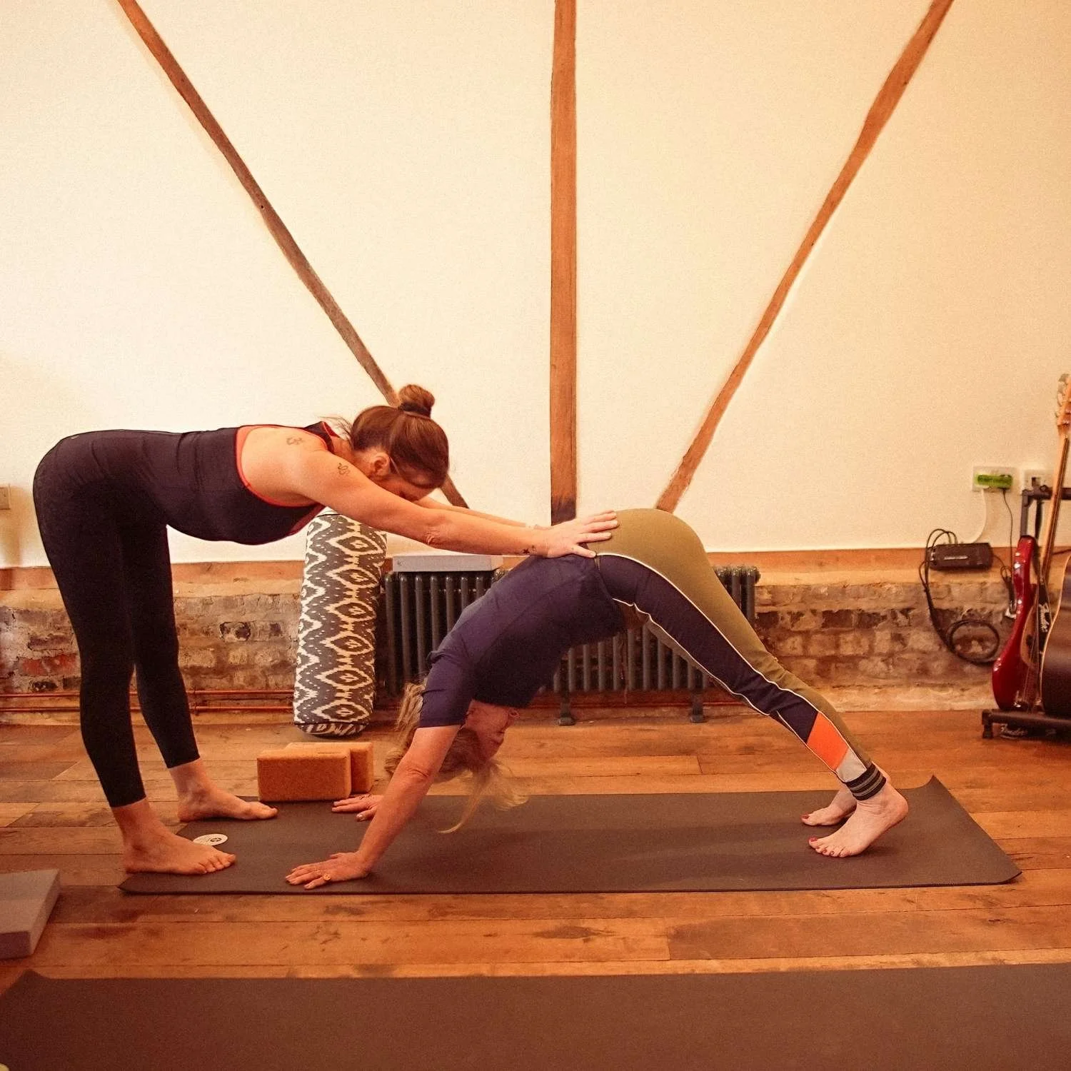 Yoga instructor assisting a woman in a yoga pose in a one-to-one home visit.