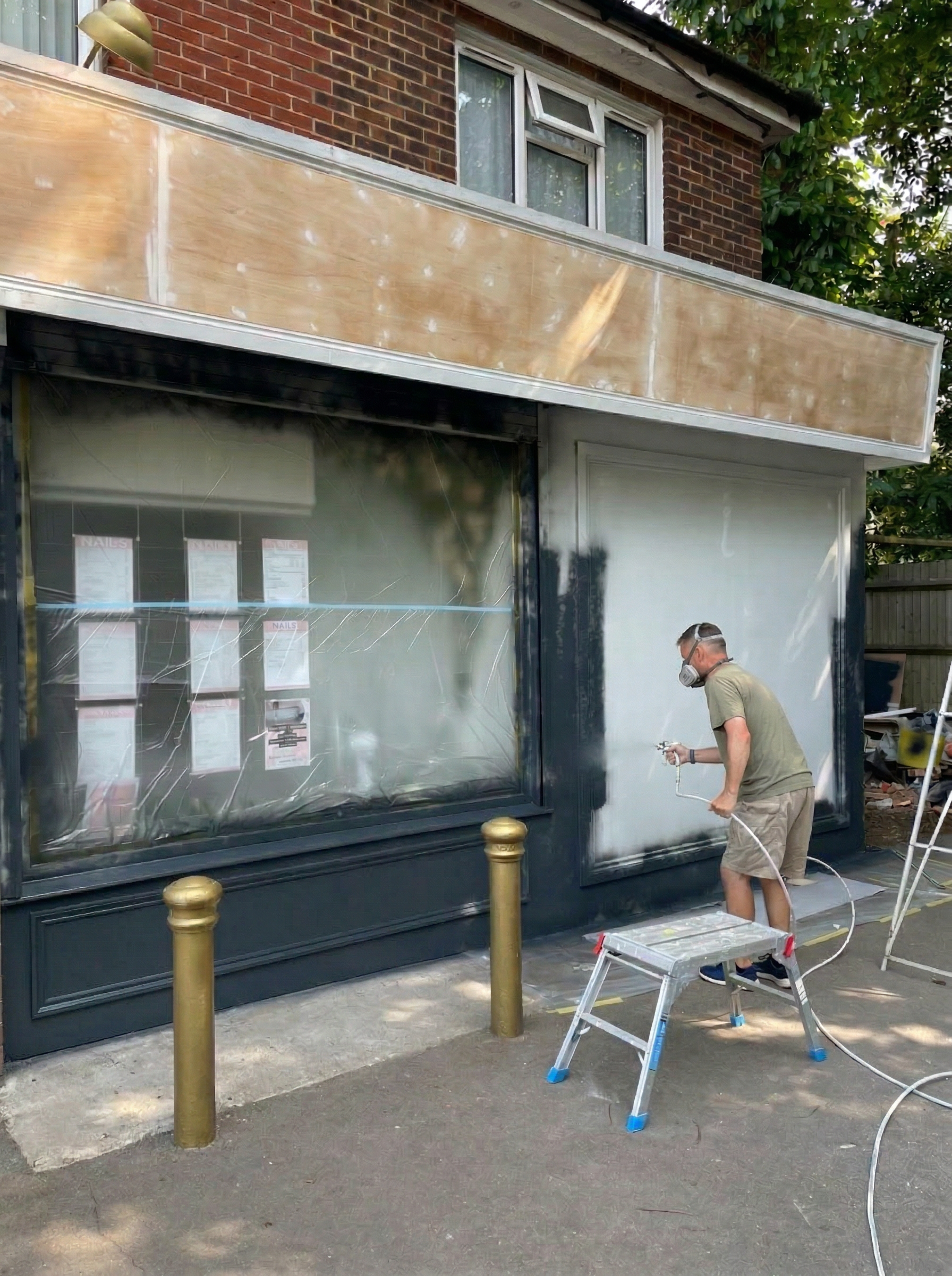 Exterior commercial business premises during airless spraying and restoration work.