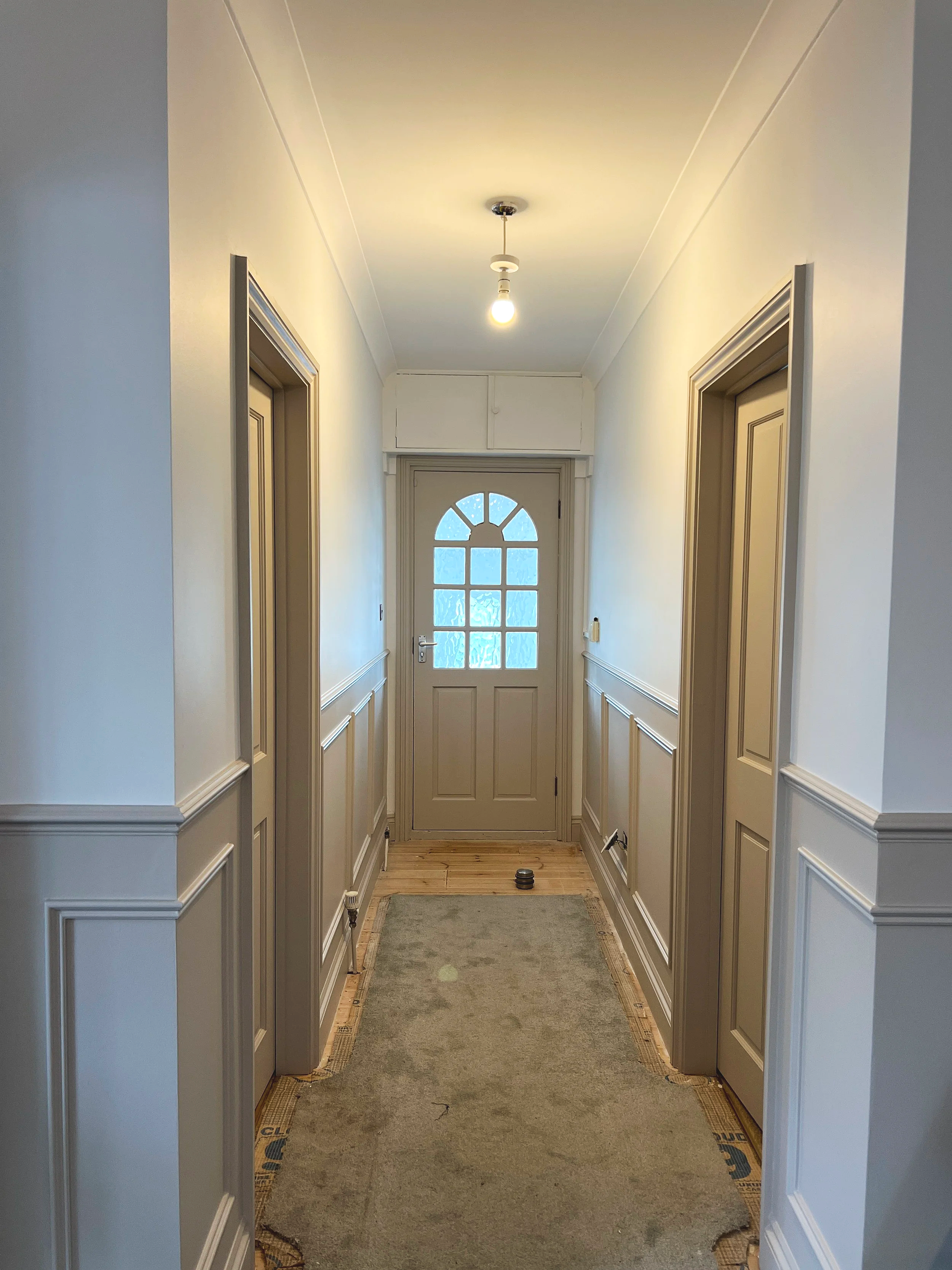 Residential entrance freshly decorated with cream walls and beige detail finishing on the doors and paneling