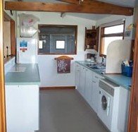 Organised and sectioned kitchen with refrigerator, washing machine, stove, and window