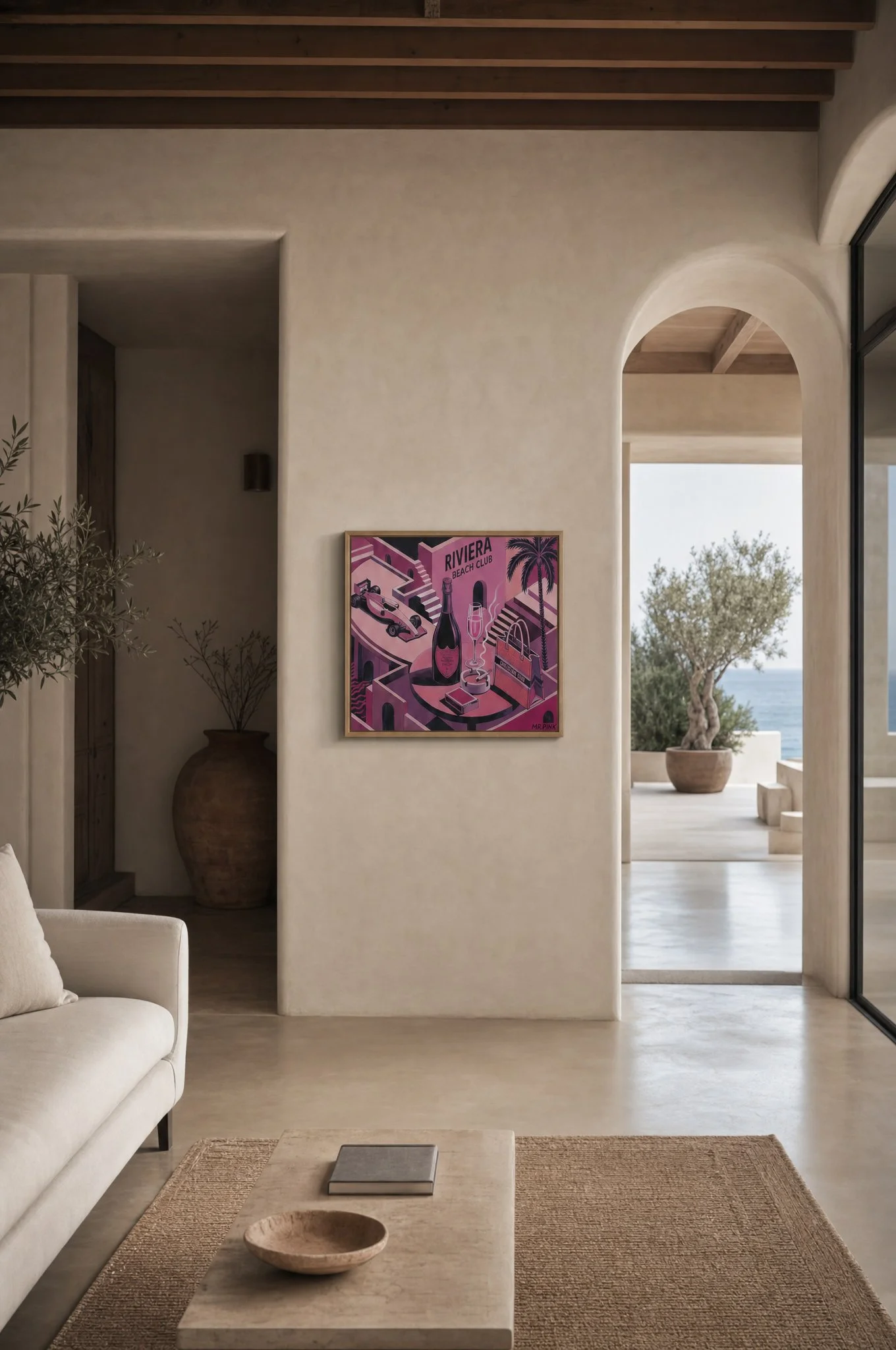 Intérieur d'un salon minimaliste avec un canapé blanc, une table en marbre avec un bol en bois et un livre, un tapis en jute, une peinture colorée sur le mur, une porte cintrée et une vue sur un jardin avec un arbre et la mer en arrière-plan.