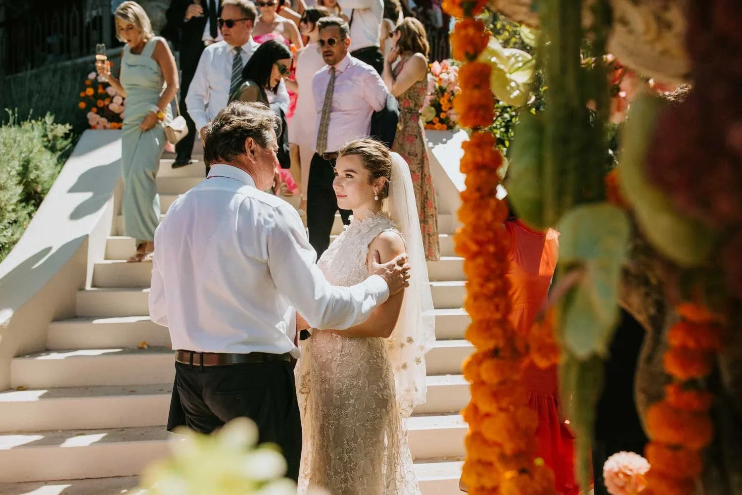 Bride sharing a quiet conversation with her father on the staircase of her childhood home in Tamboerskloof after the wedding ceremony as guests gather in the background.