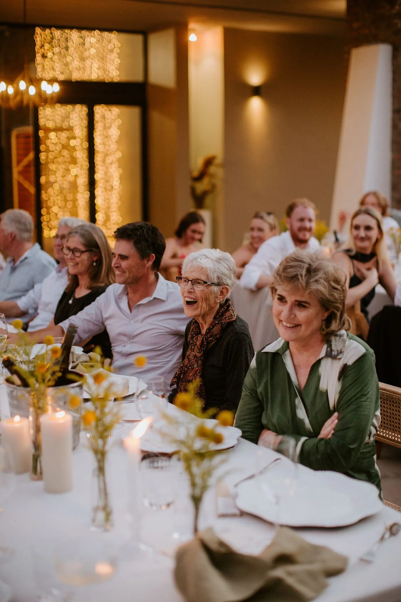 Wedding guests enjoying speeches and laughing together during the reception dinner.