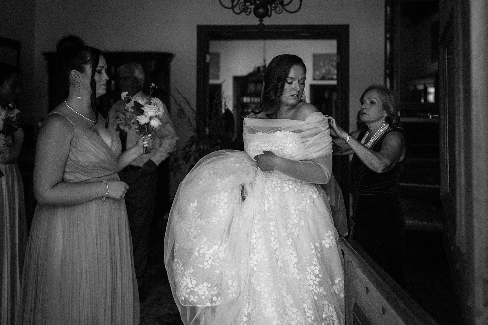 Black-and-white photograph of a bride getting ready with family members before her wedding ceremony.