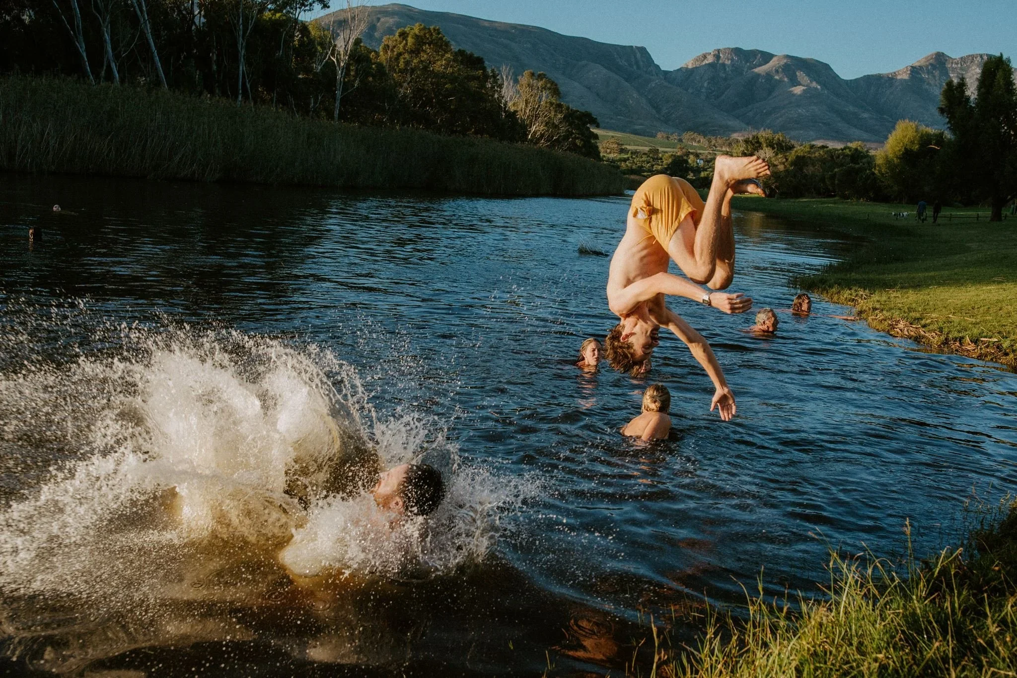 Groom jumping into a river after the wedding lunch in Stanford.
