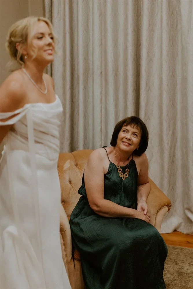 Bride's mother smiling up at her daughter as they share a quiet moment before the ceremony at Langkloof Roses.