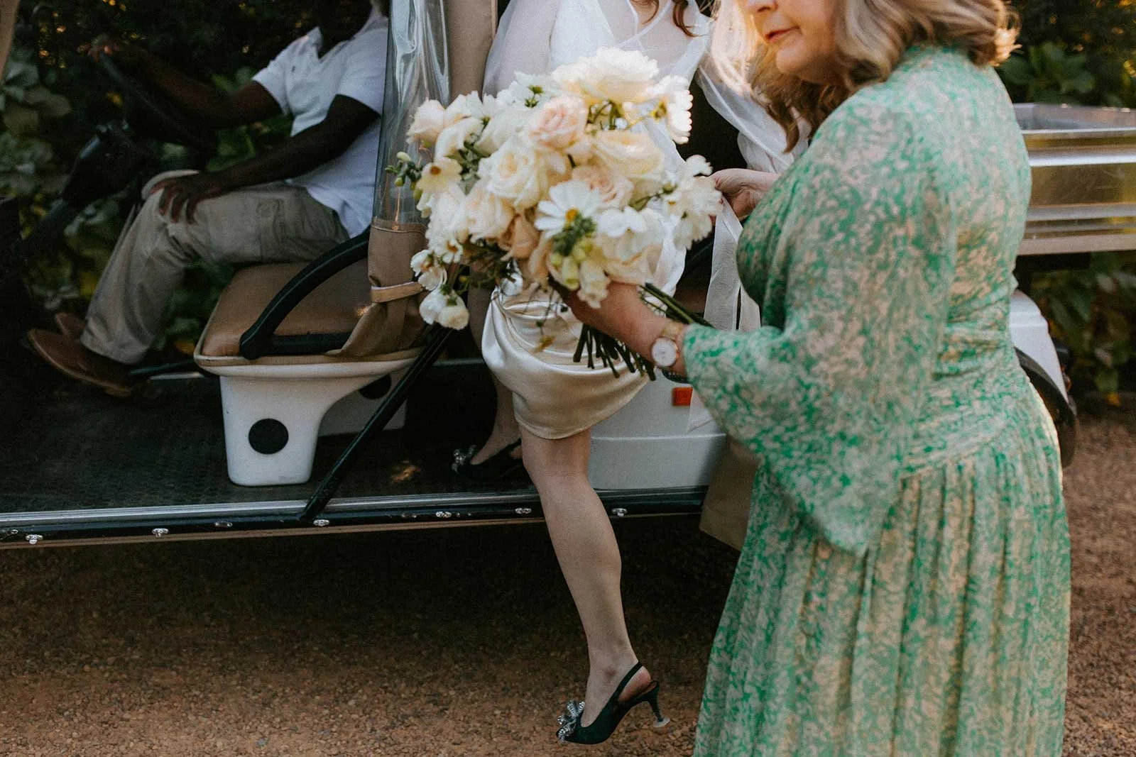 A bride standing next to her mother in a green patterned dress, who is handing her the bouquet. Wedding in Cape Town, South Africa captured by wedding photographer Marli Koen.