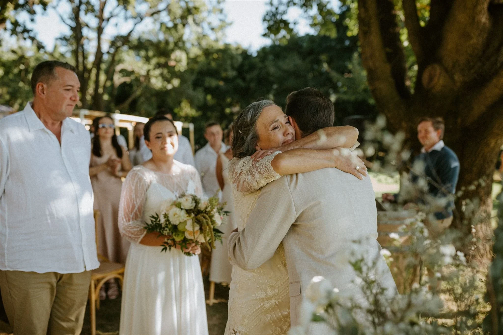 Bride's mother embracing the groom before the ceremony as the bride and her father look on at Saronsberg Cellar.