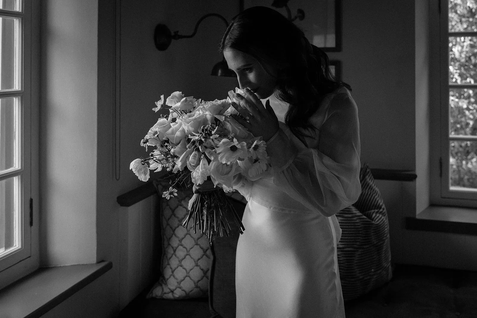 Bride pausing by a window with her bridal bouquet before the wedding ceremony at Boschendal Olive Press.