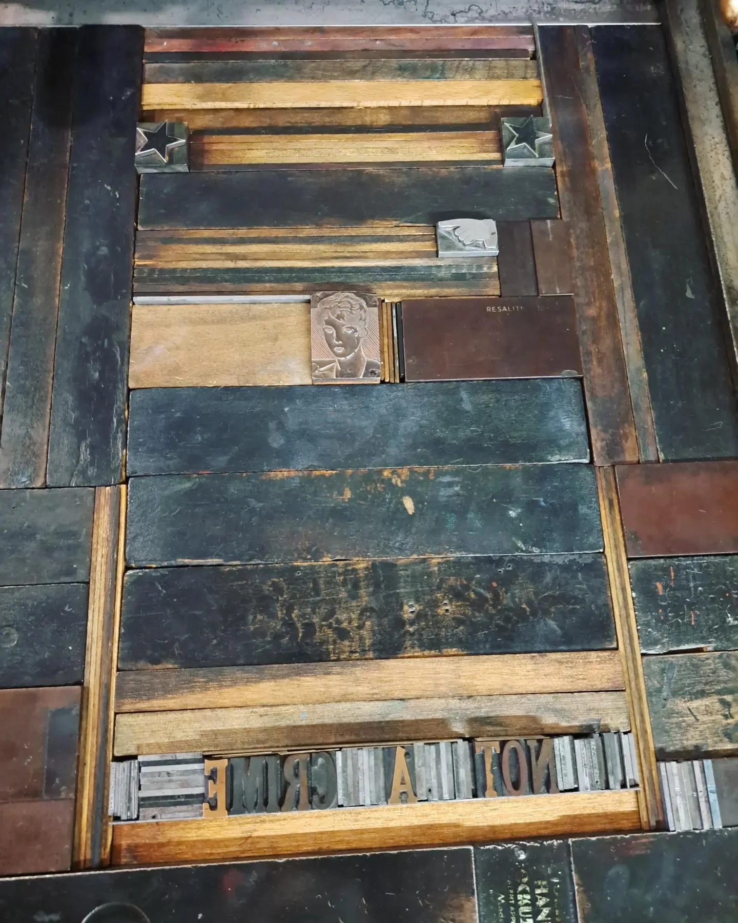 Process photo of vintage wooden letterpress type locked into a metal printing chase for the “Drag Is Art” poster series.