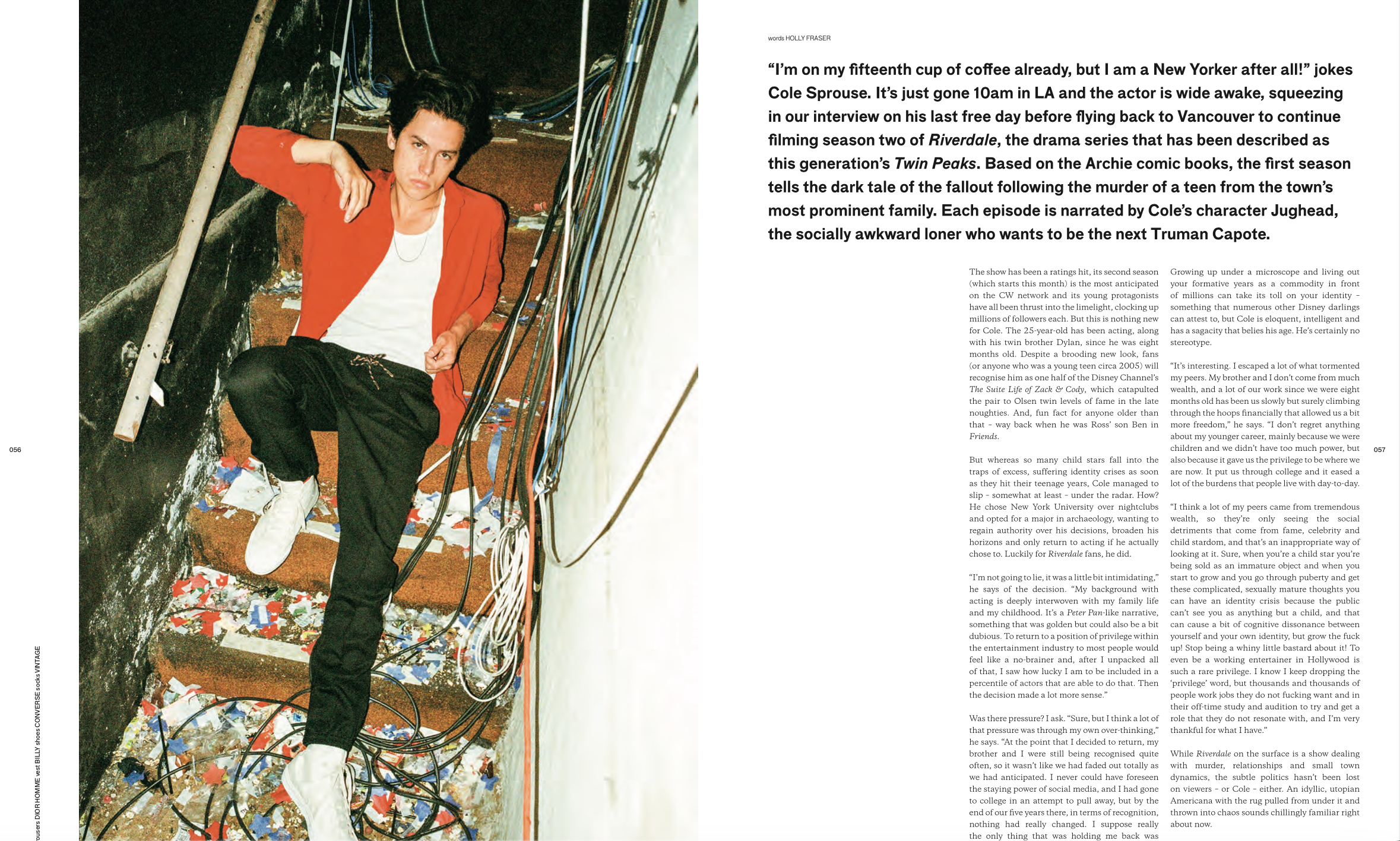A young man with dark, styled hair is lying down in an industrial or backstage setting, surrounded by tangled wires, with colorful confetti scattered on the floor around him. He is wearing a red jacket, a white shirt, and white sneakers, with a serious expression on his face.