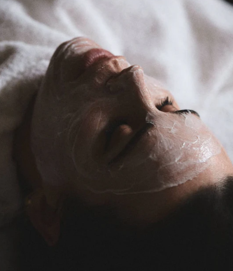 Close-up of a person lying down with a face mask applied, eyes closed.