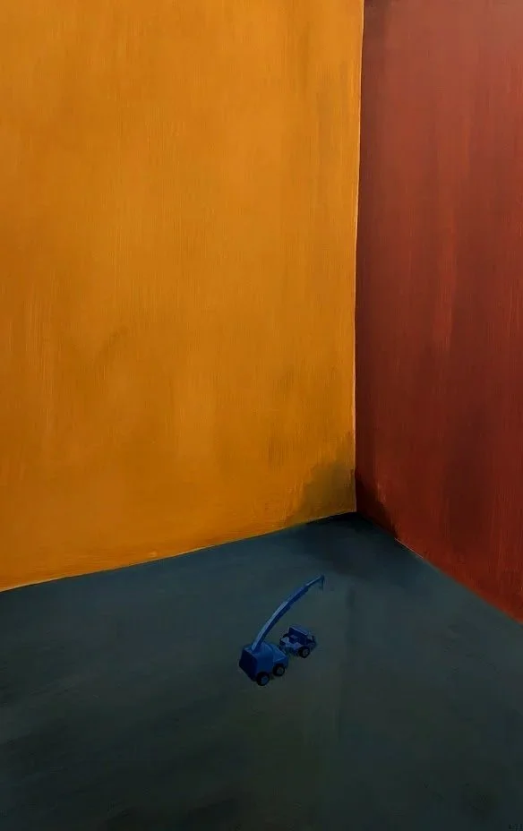 Small toy truck with a crane arm on a floor, near the corner of two colorful walls, one yellow and one red.
