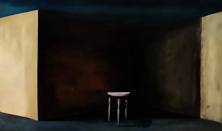 A small round white table with three black legs in a dark, empty room with yellow and black walls.