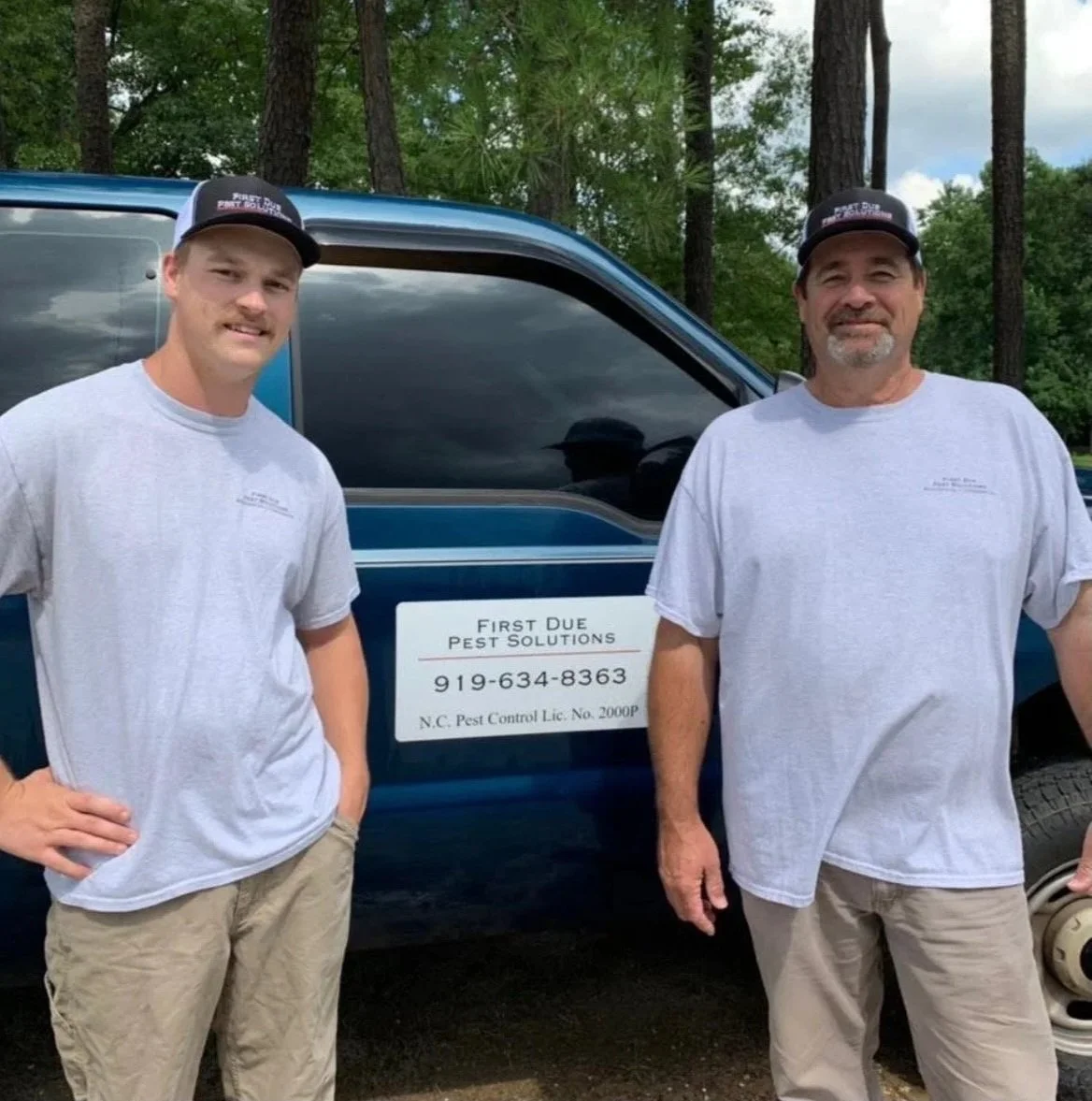 Two pest control professionals in front of a First Due Pest Solutions truck that is licensed and insured.