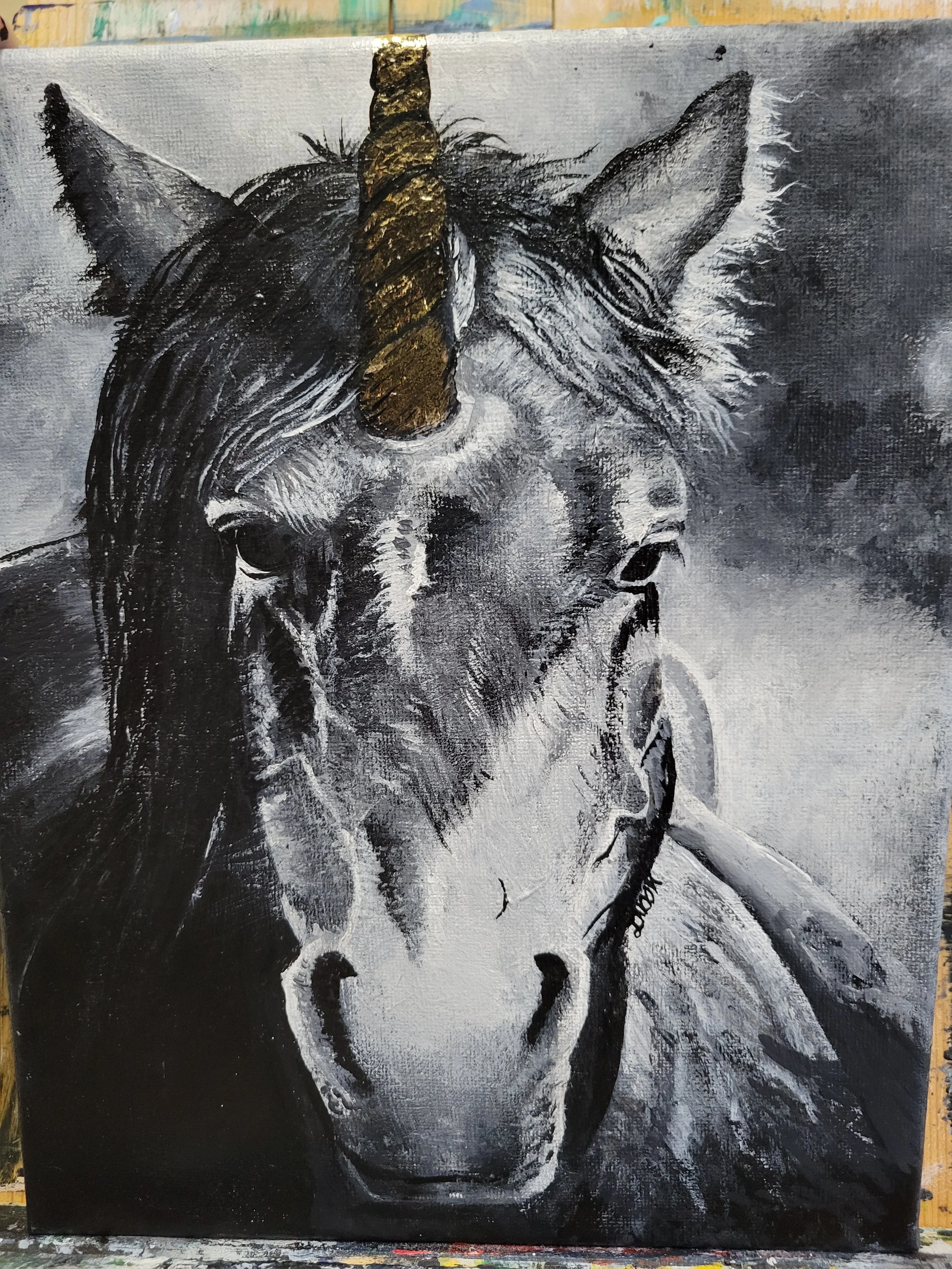 Painting of a unicorn's head in black, white, and gray tones with a prominent golden horn. The unicorn appears to be smoking a cigarette.