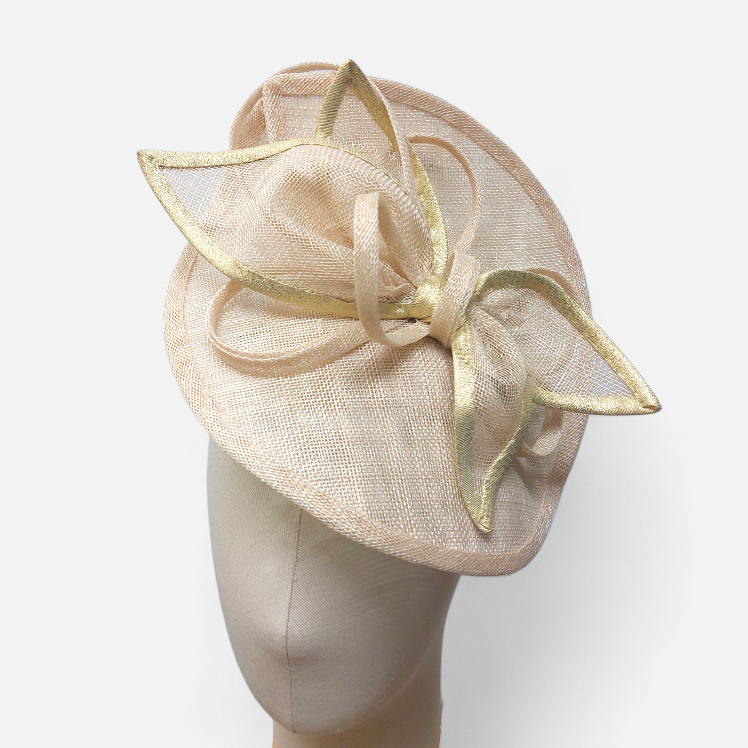 Elegant soft gold John Paul Millinery hat with a large bow and gold-trimmed leaves, displayed on a mannequin head.