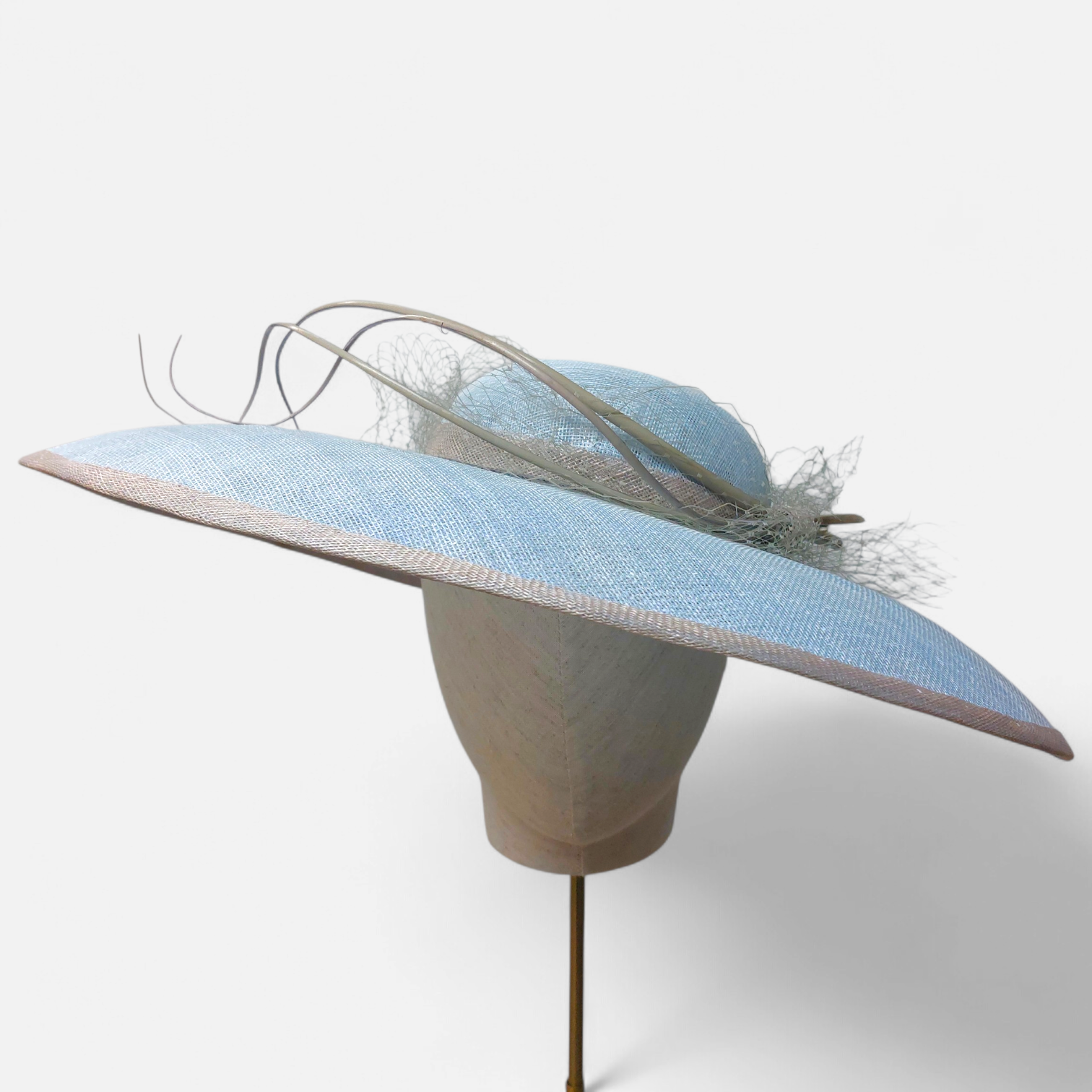 A decorative hat with a wide blue brim and low crown from John Paul Millinery