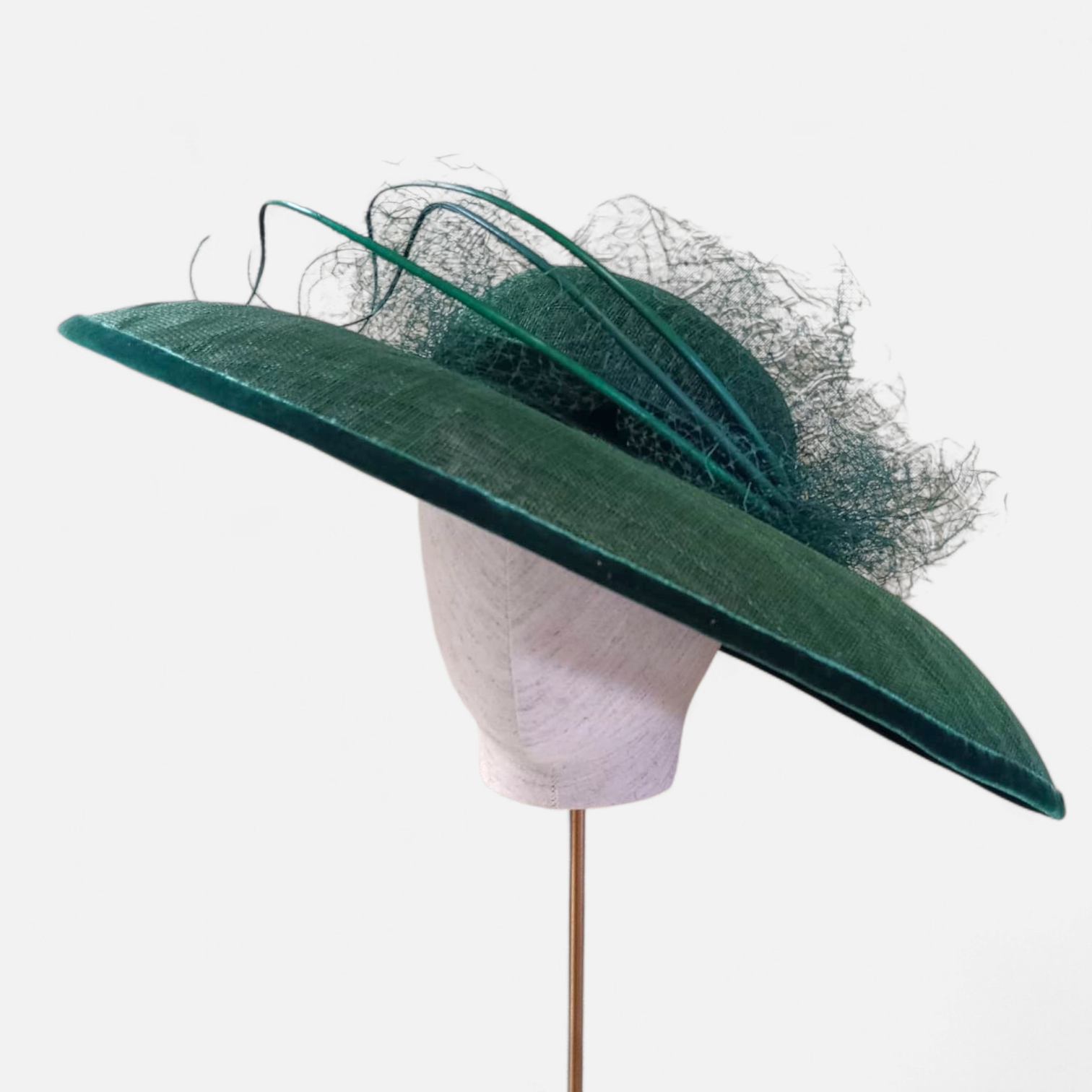 Elegant green John Paul Millinery hat with large brim and decorative netting, displayed on a mannequin head.