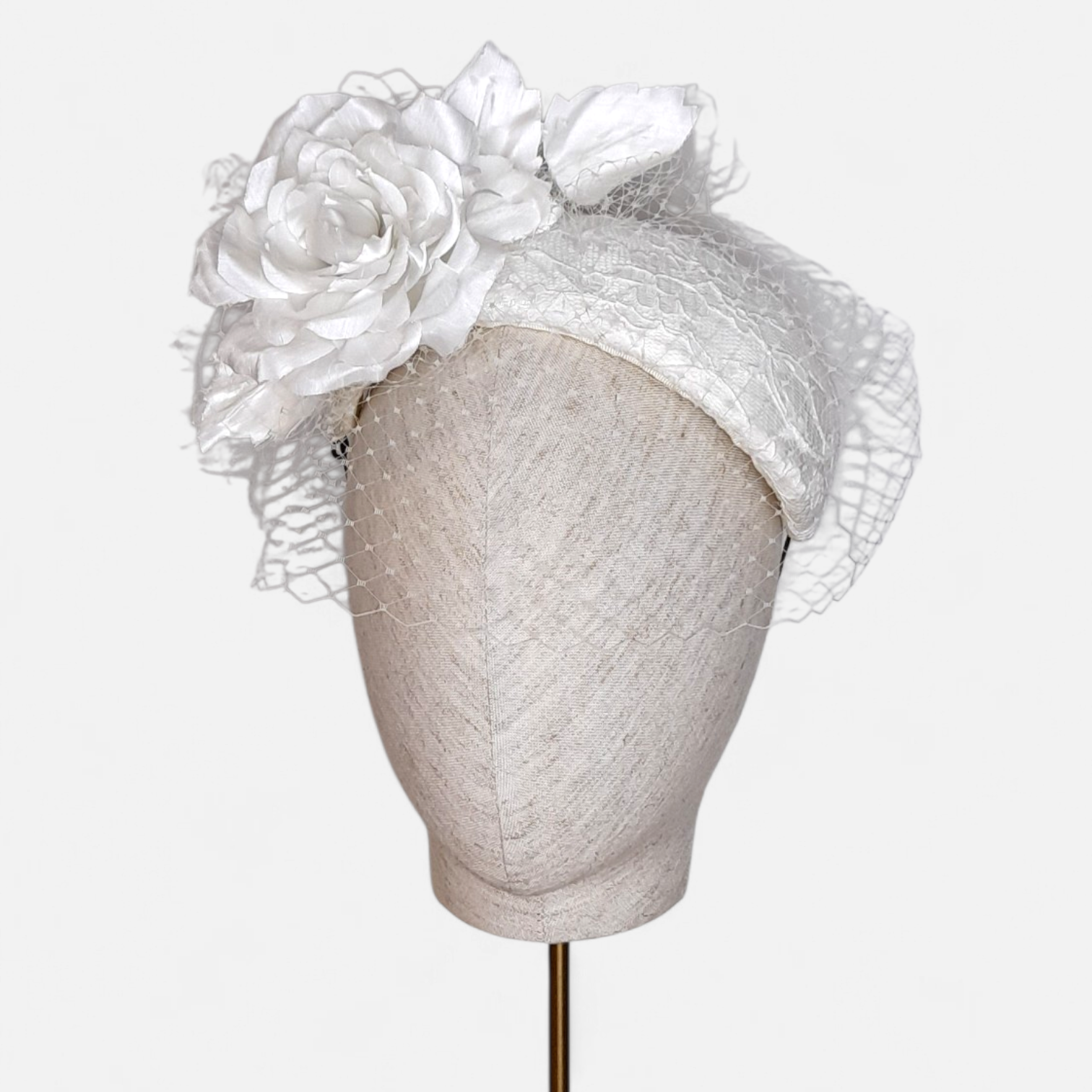 White bando style halo fascinator with large fabric flowers, lace, and a net veil, by John Paul Millinery