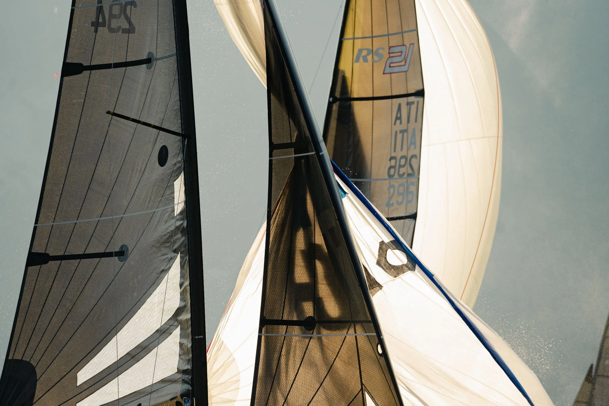 Immagine di due barche a vela con le vele gonfie in mare, con il cielo nuvoloso sullo sfondo.
