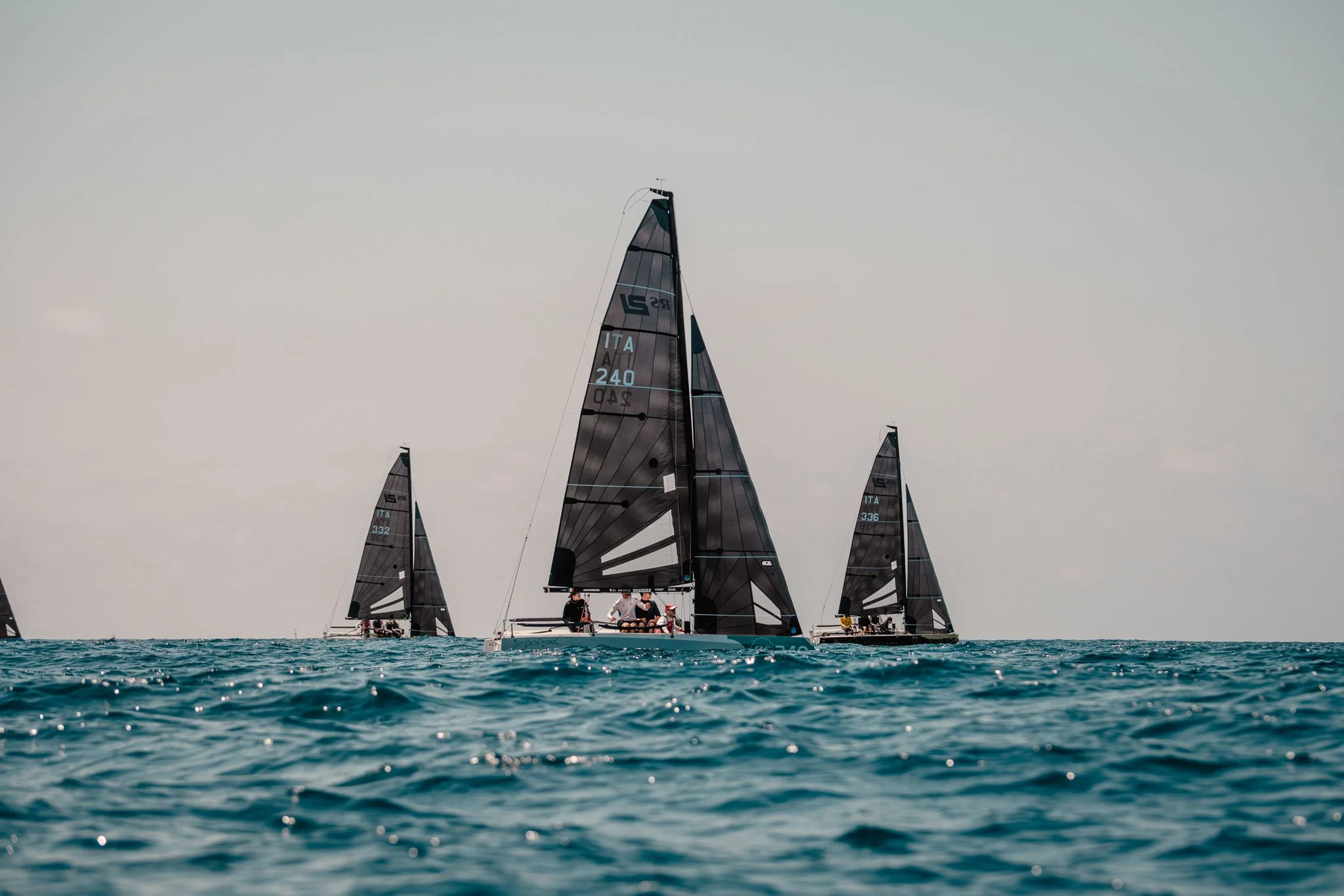 Yacht a vela con vele nere con persone a bordo in acqua aperta