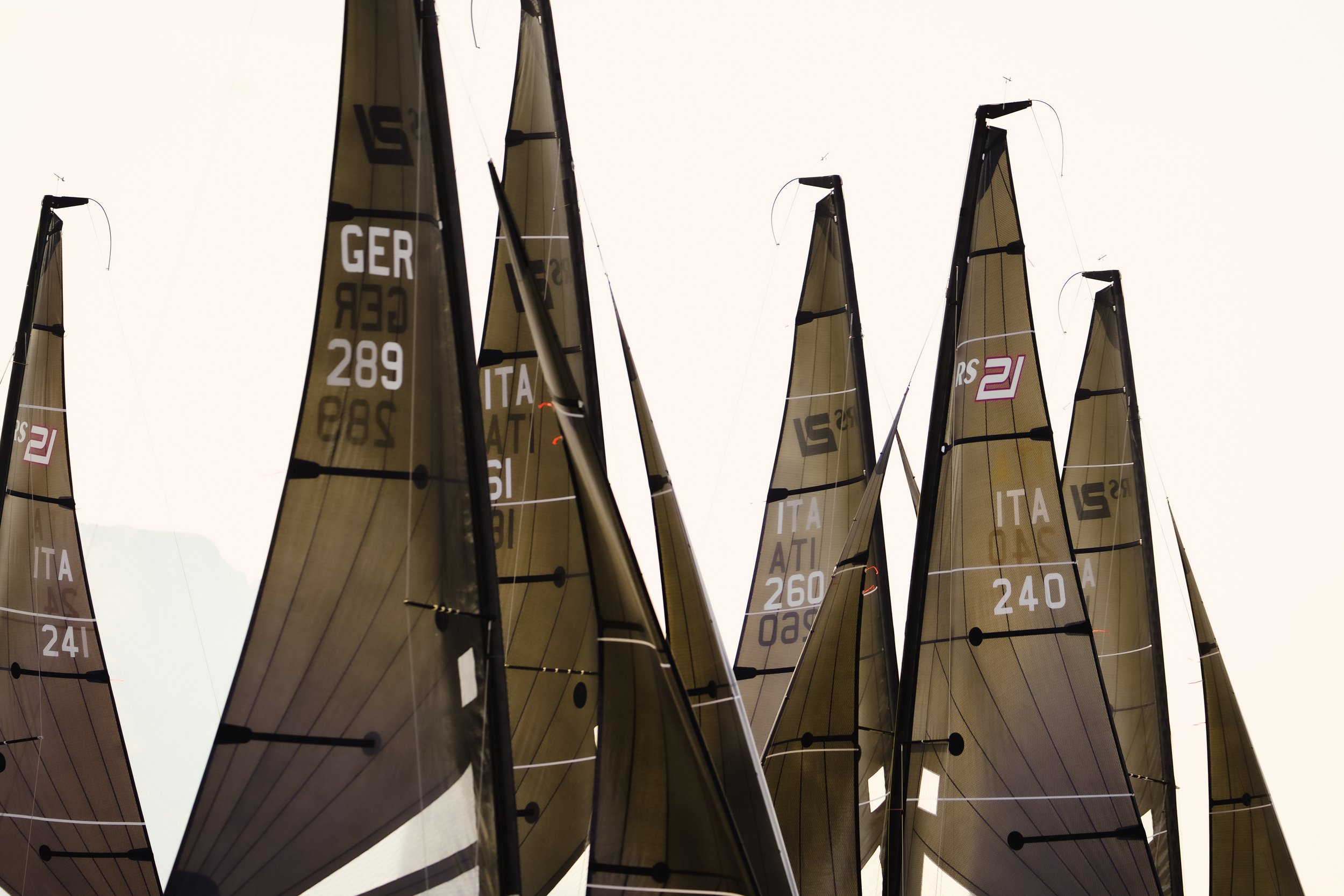 Più vele da regata in legno e carbonio con numeri e lettere, esposte una accanto all'altra