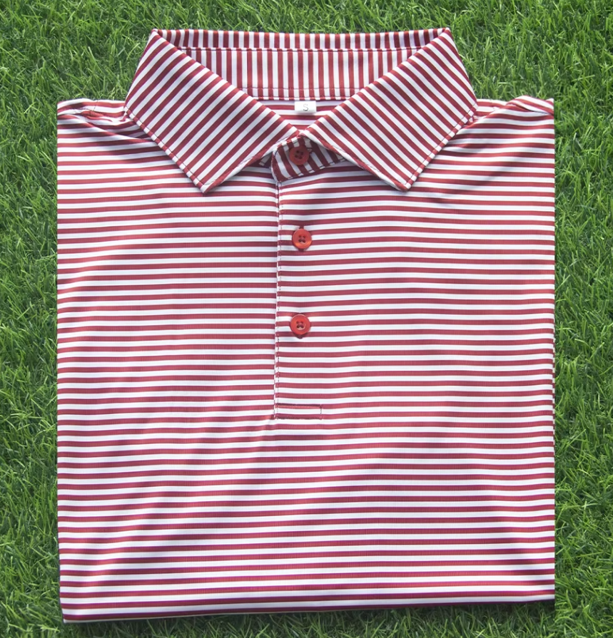 Red and white striped polo shirt folded on green grass.