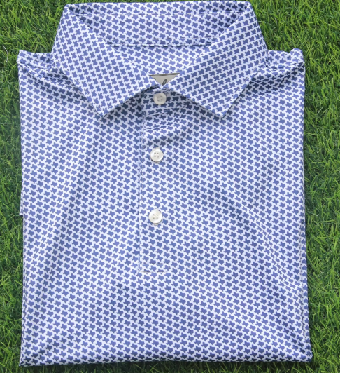 A folded blue and white patterned dress shirt on green grass.