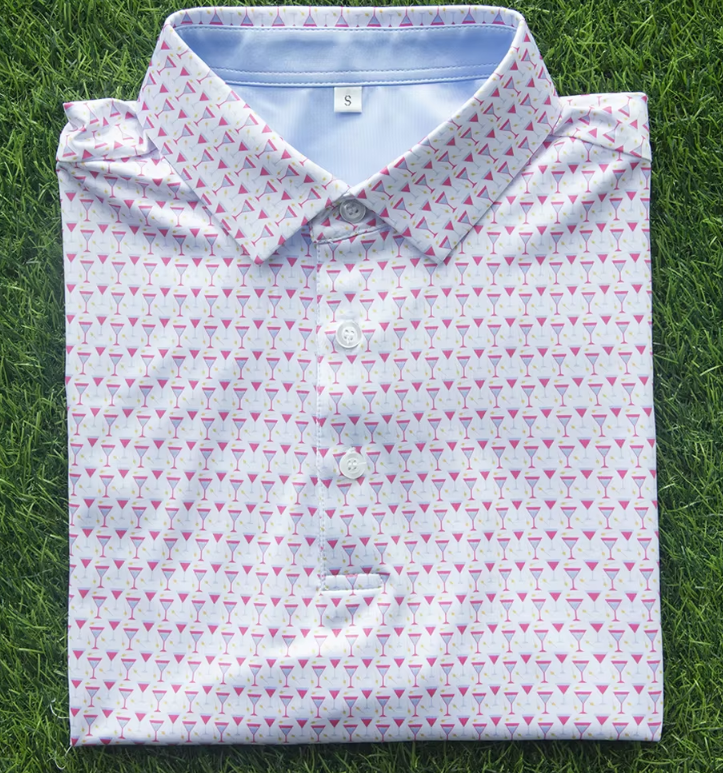 Folded men's collared shirt with a pink and white geometric pattern, lying on green grass.
