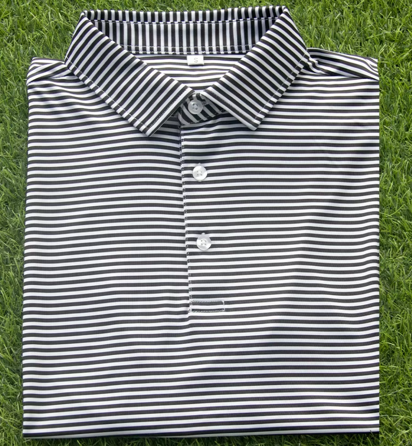 A folded black and white striped polo shirt laying on green grass.