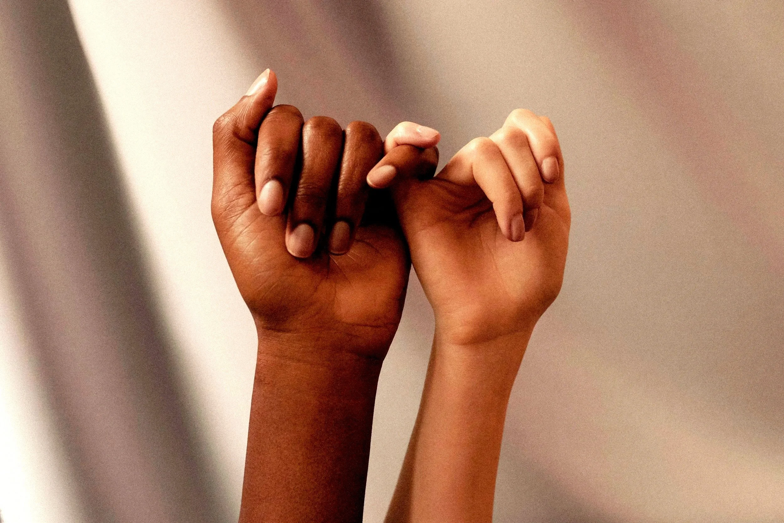 Deux mains de différentes couleurs de peau qui se tiennent ensemble, symbolisant l'unité et la solidarité.