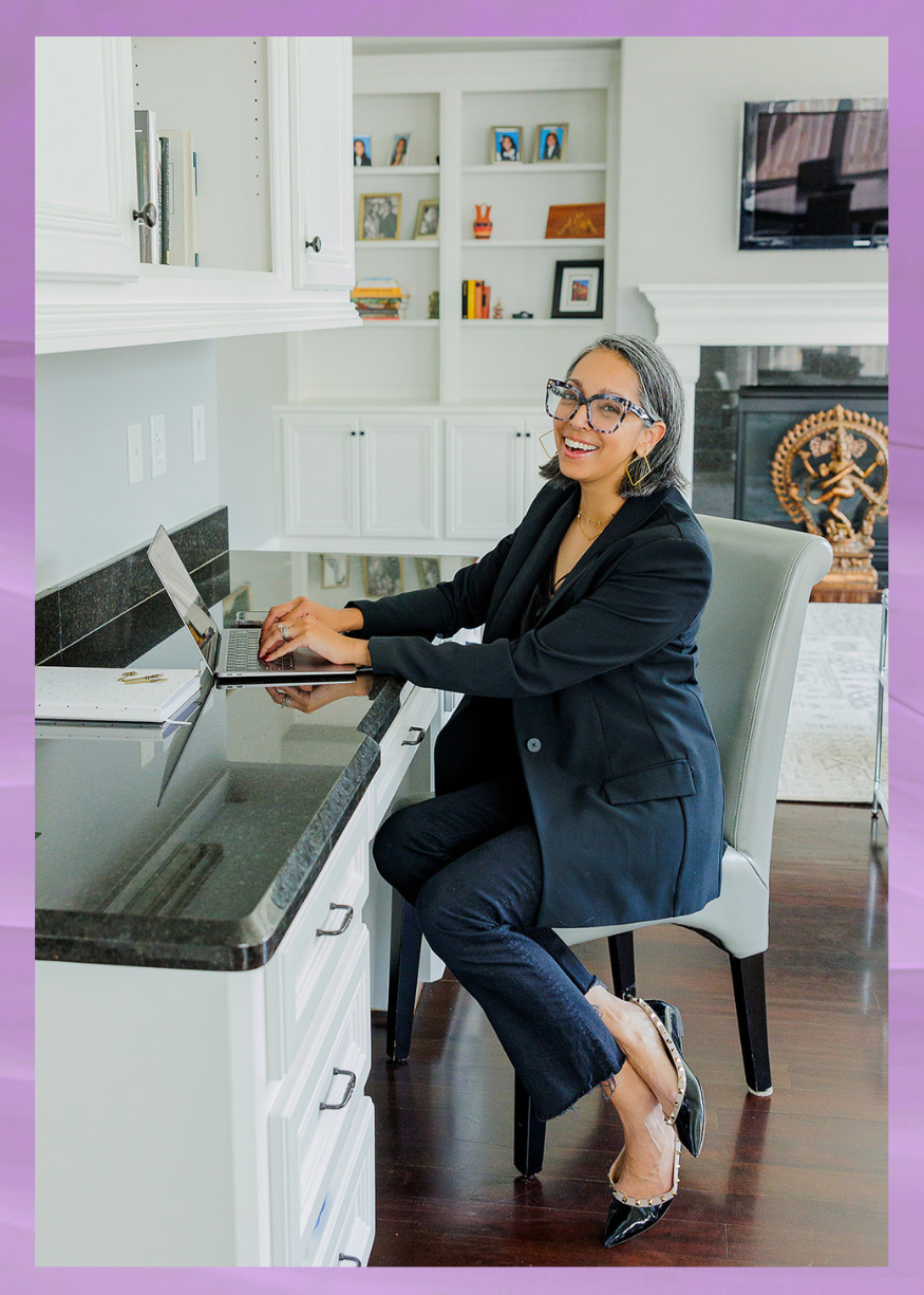 Aditi Pemmaraju, Houston physician relocation realtor, working on a laptop in a home office and smiling.