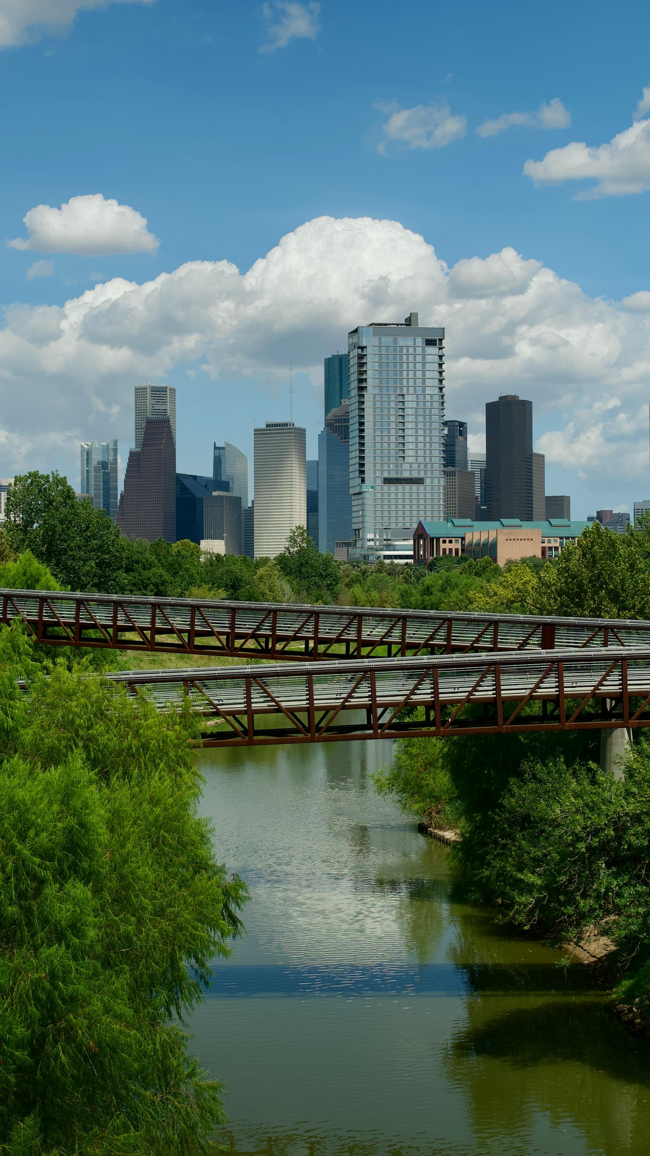 Houston skyline with park, river, and bridges, representing neighborhoods near the Texas Medical Center for relocating physicians.