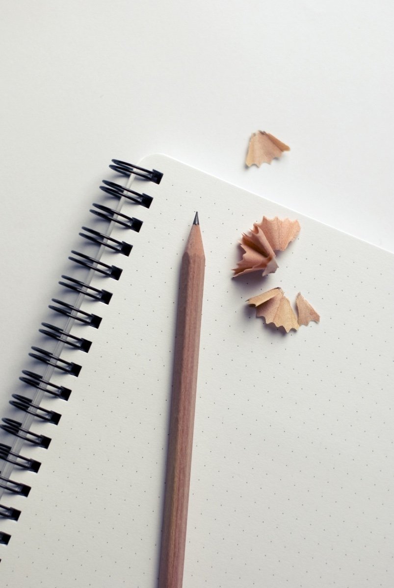 Sharpened wooden pencil on a spiral notebook with scattered pencil shavings