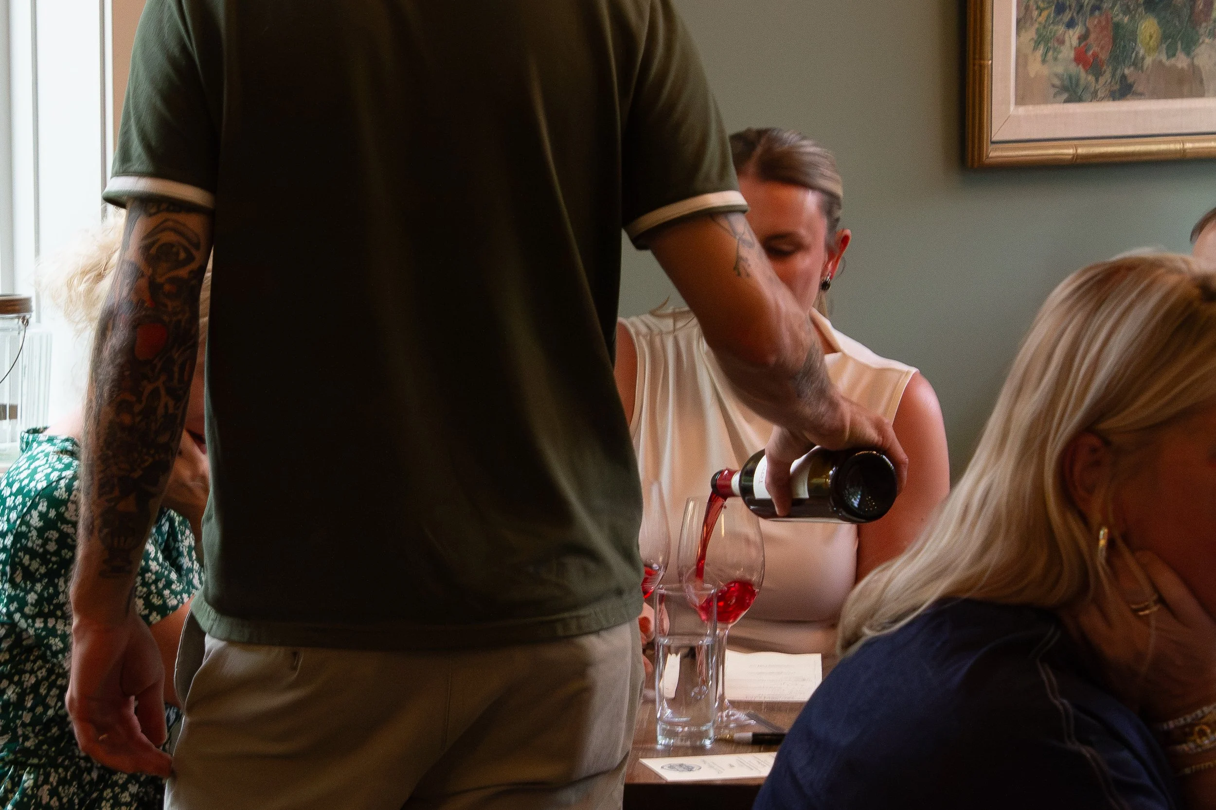 Guest pouring wine at a Traveler’s Table wine dinner.