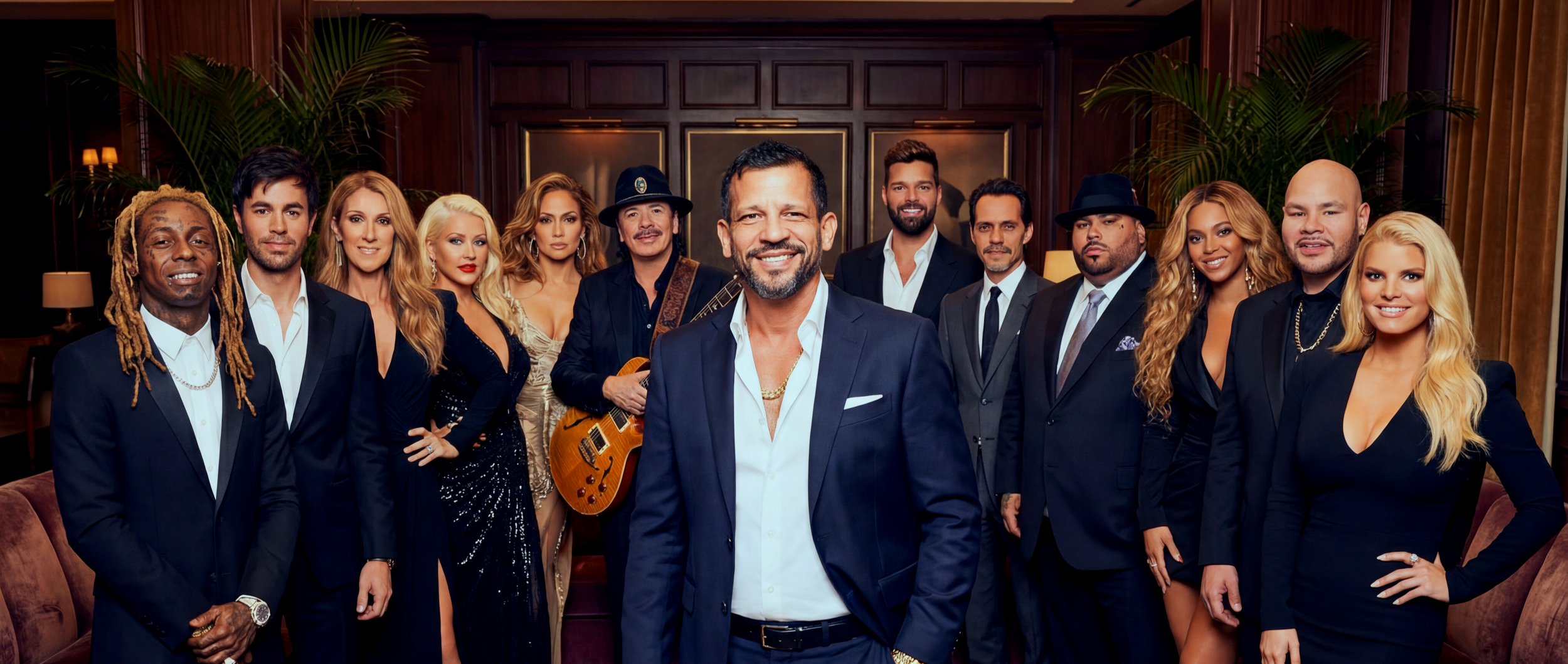 Group of diverse men and women dressed in formal attire in a luxurious room, posing for a photo with animated expressions.