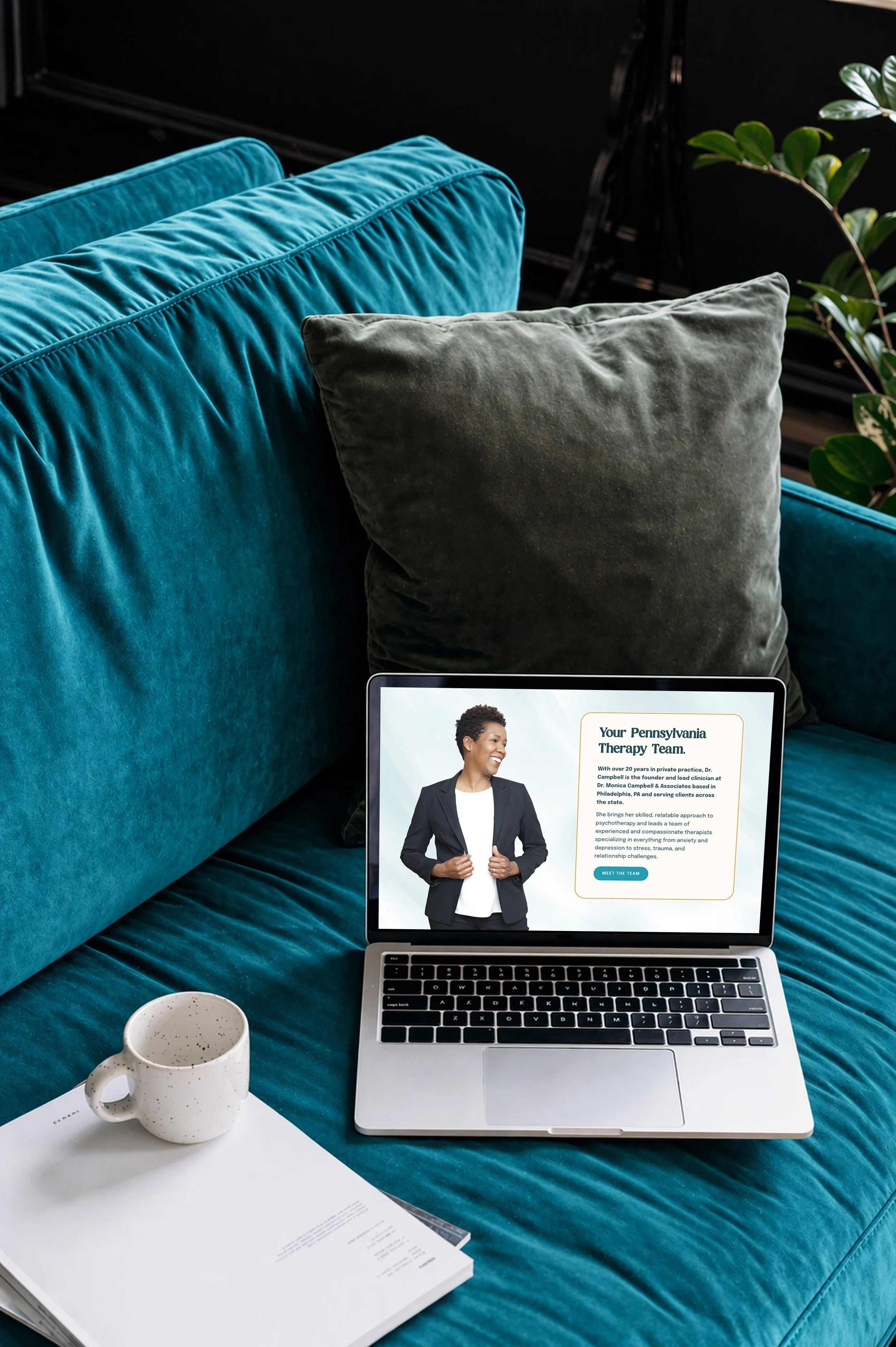 Laptop on a teal sofa showing Dr. Monica Campbell, a licensed PA therapist offering online therapy.