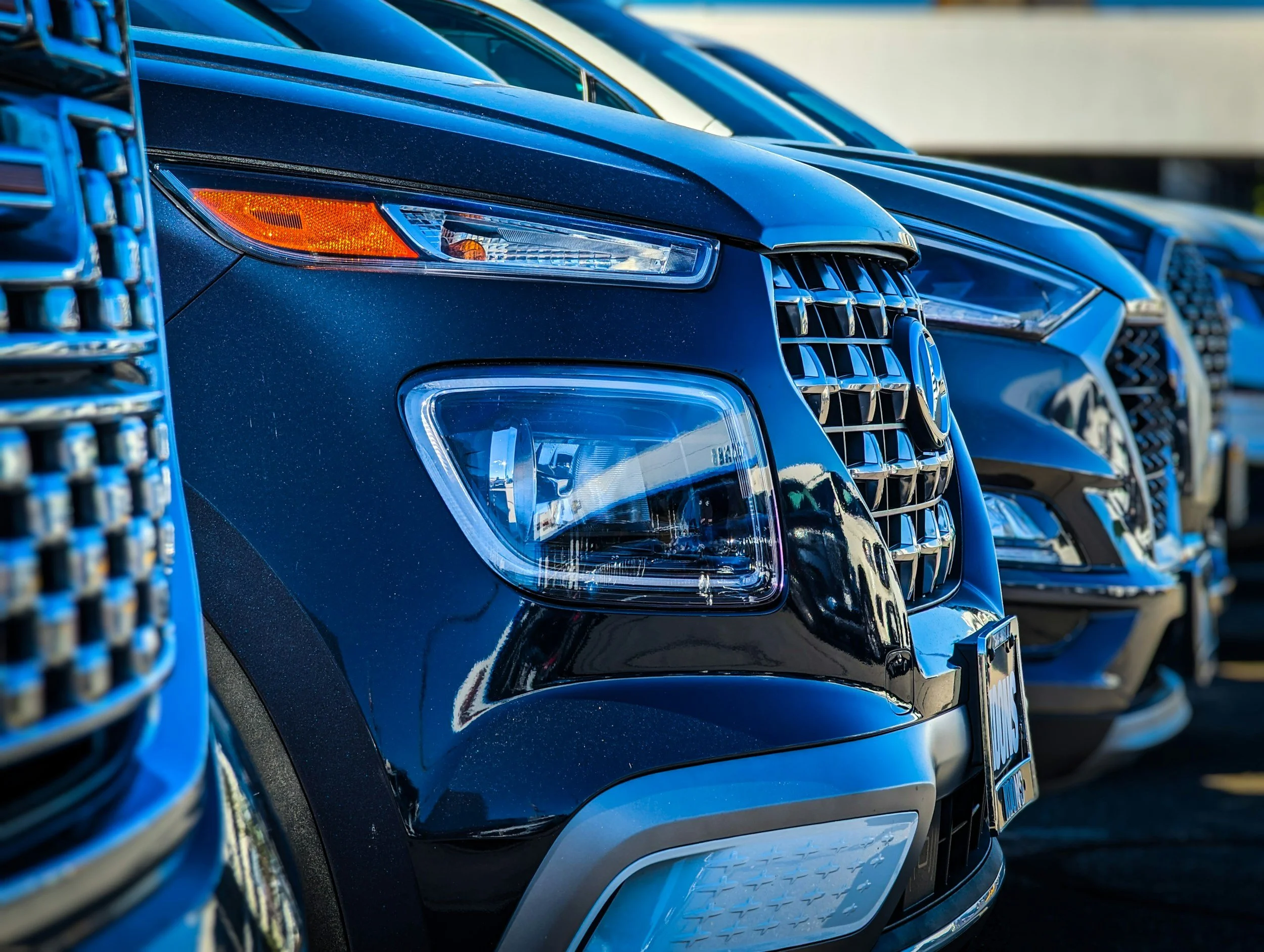 Close-up of the front of a black SUV parked in a row of cars.